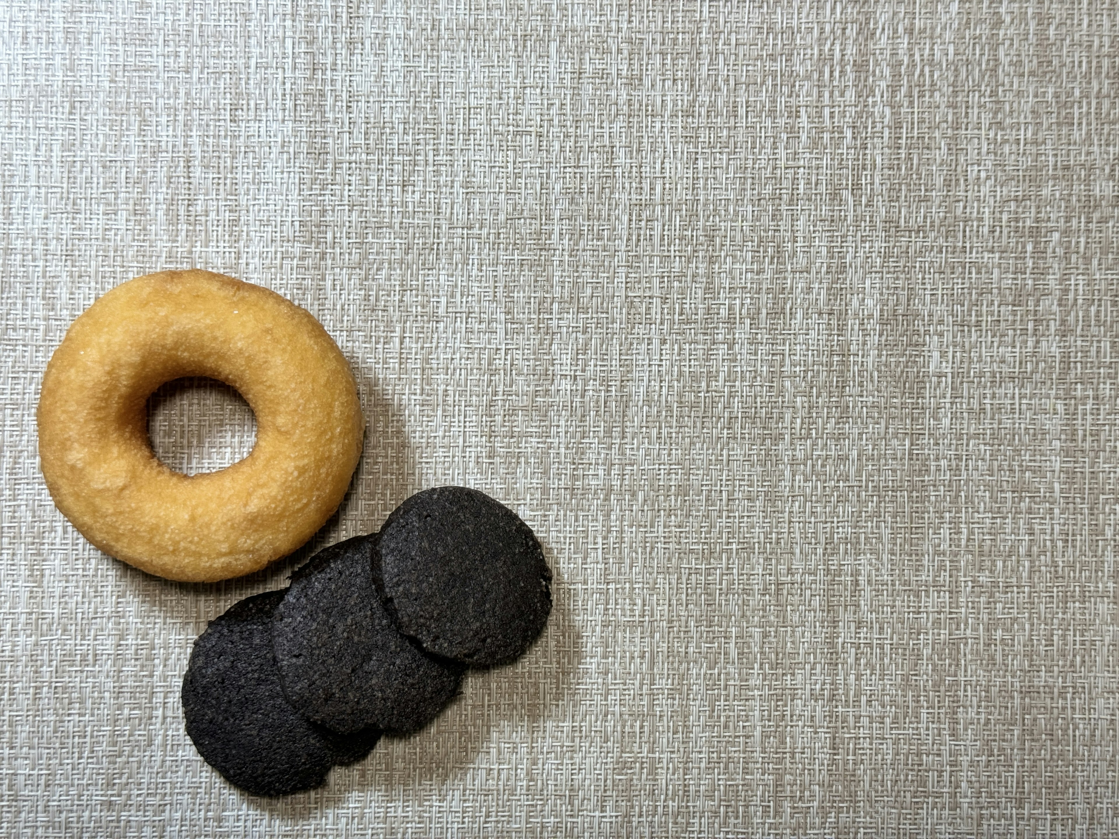 Donut beige e biscotti neri su una superficie in tessuto testurizzato