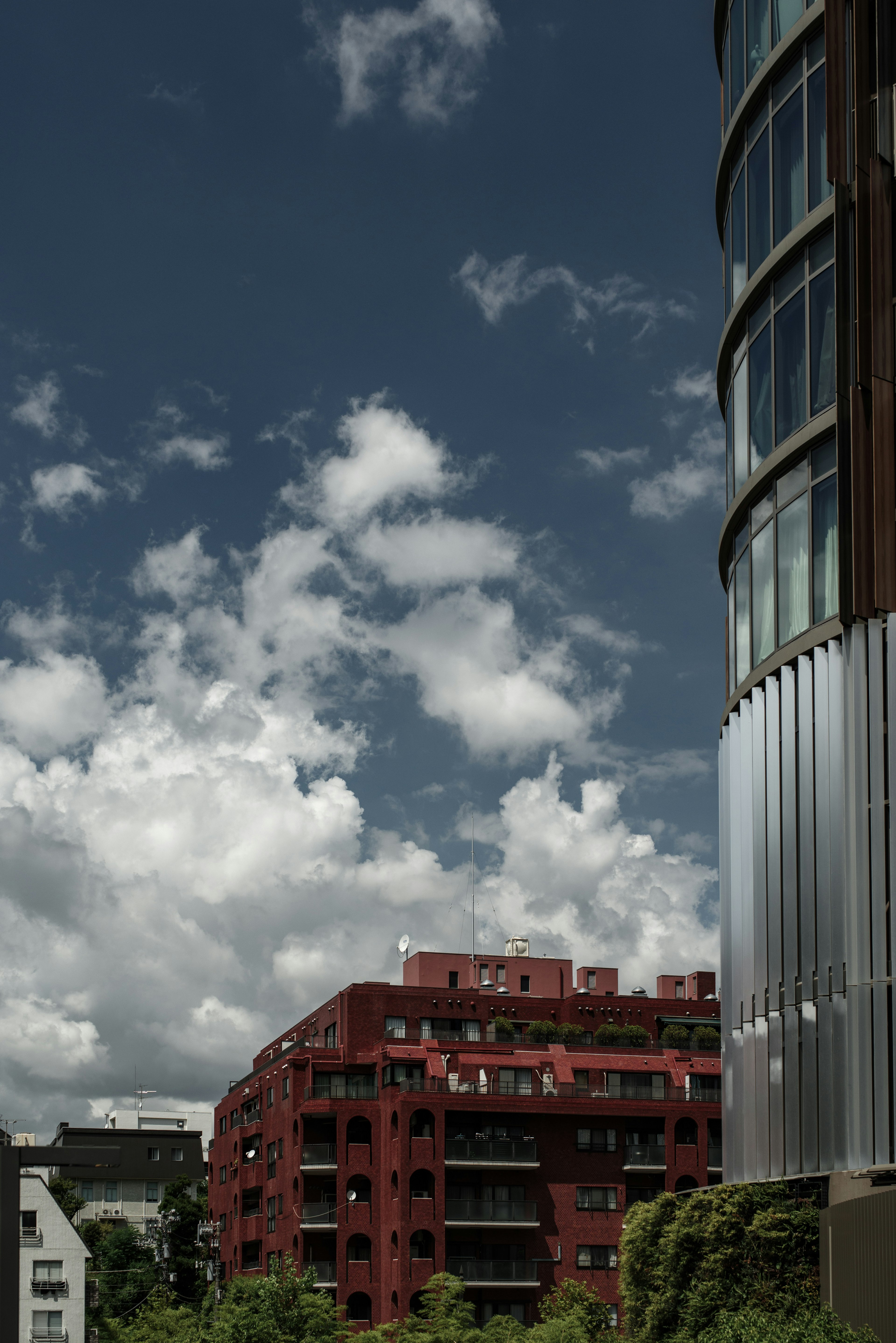 Paesaggio urbano con un edificio rosso notevole e nuvole drammatiche