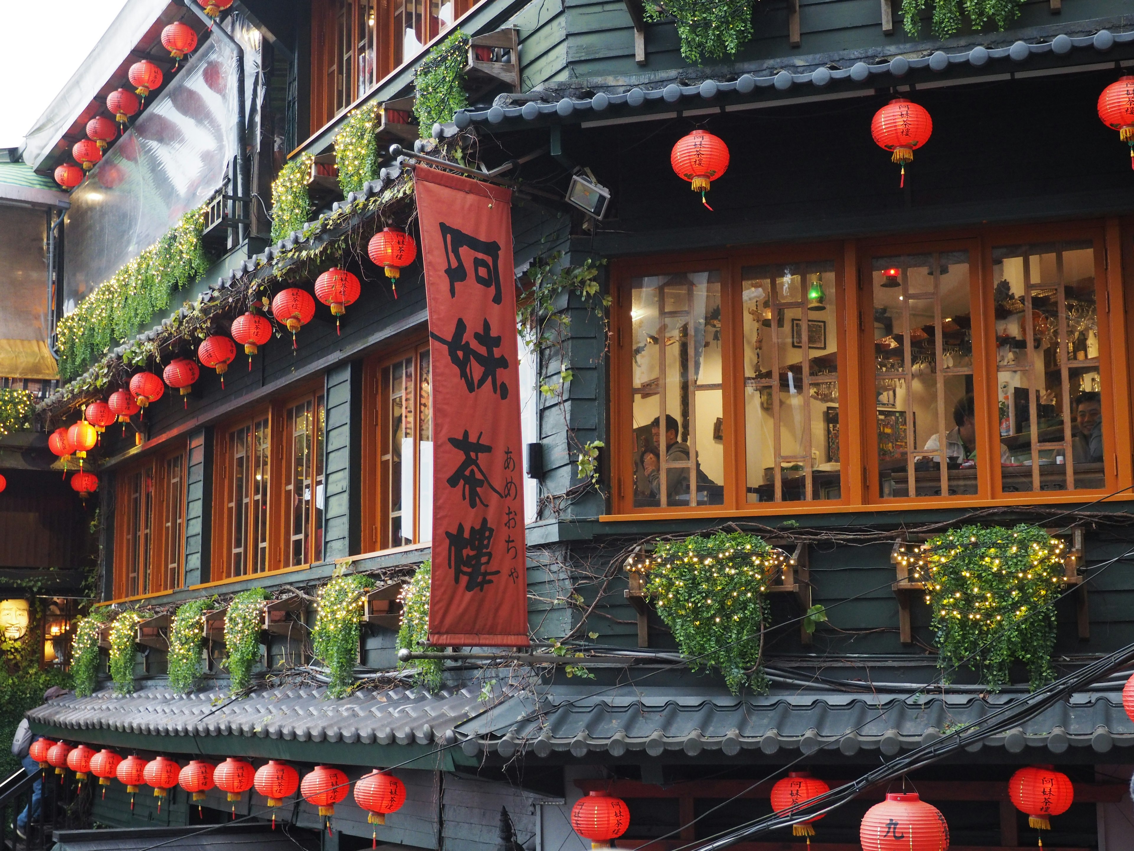 Extérieur d'un vieux bâtiment orné de lanternes rouges et de plantes vertes