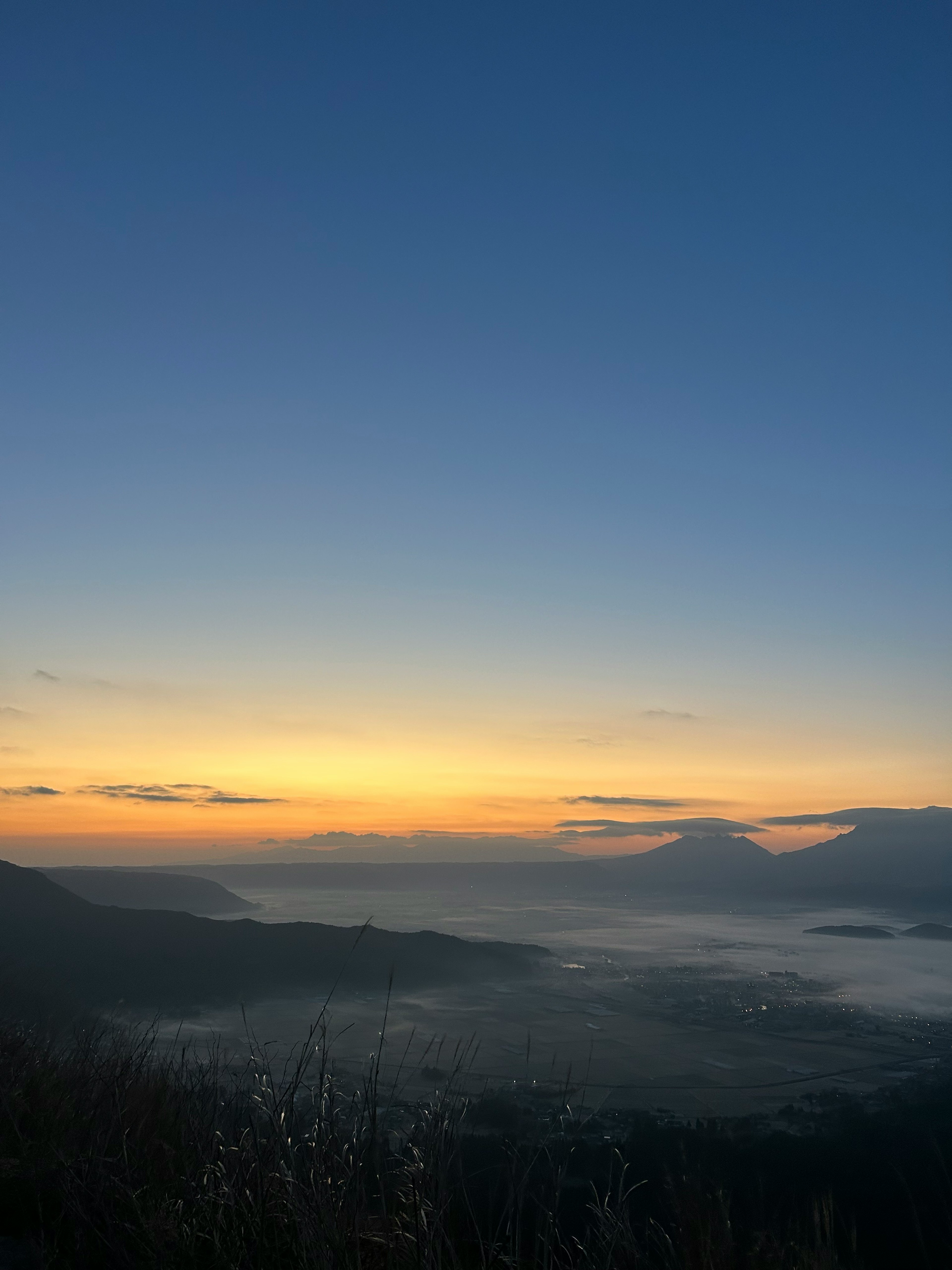 青い空とオレンジ色の朝焼けが広がる山の景色