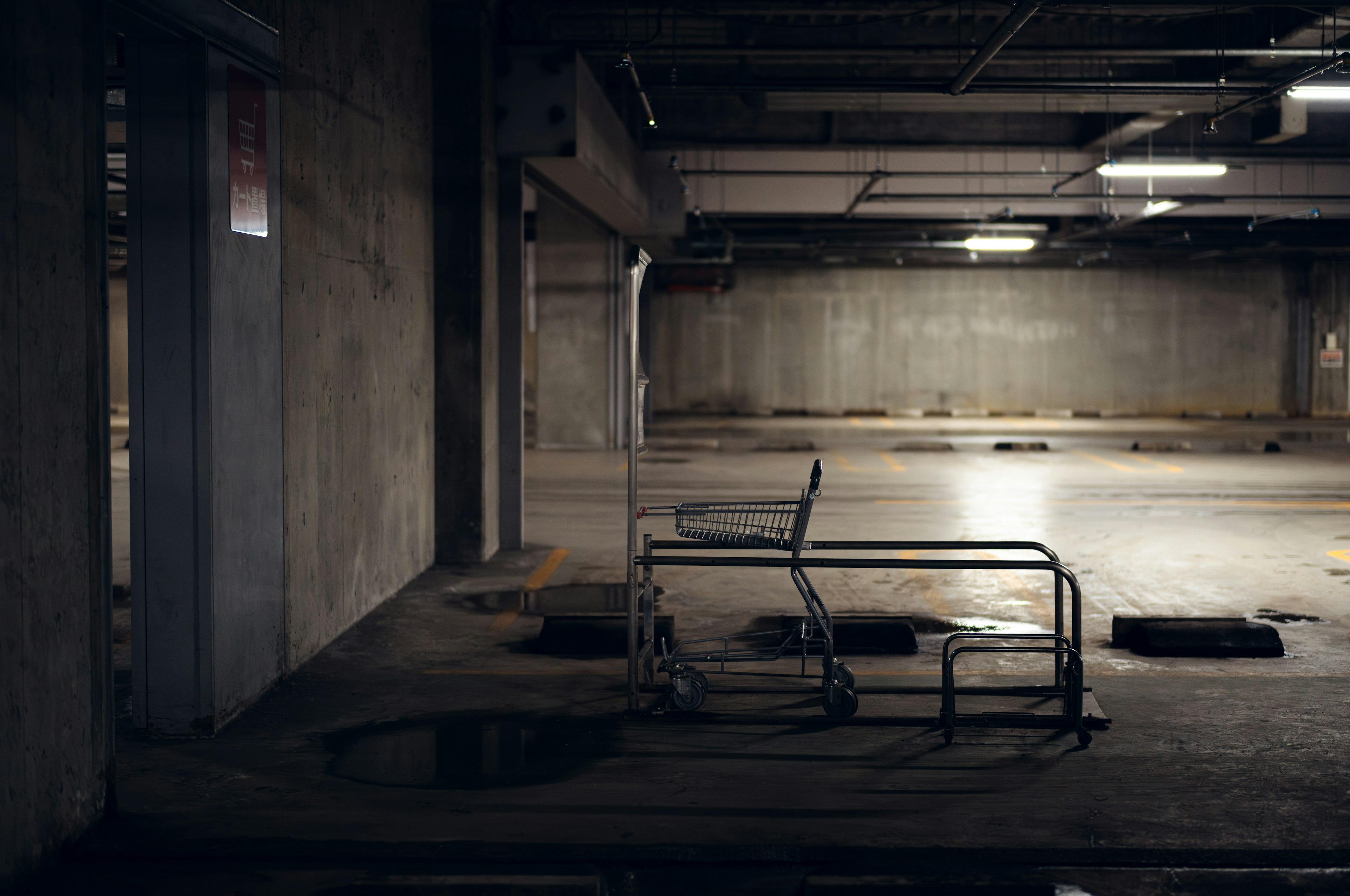 Estacionamiento abandonado con un carrito metálico y paredes de concreto