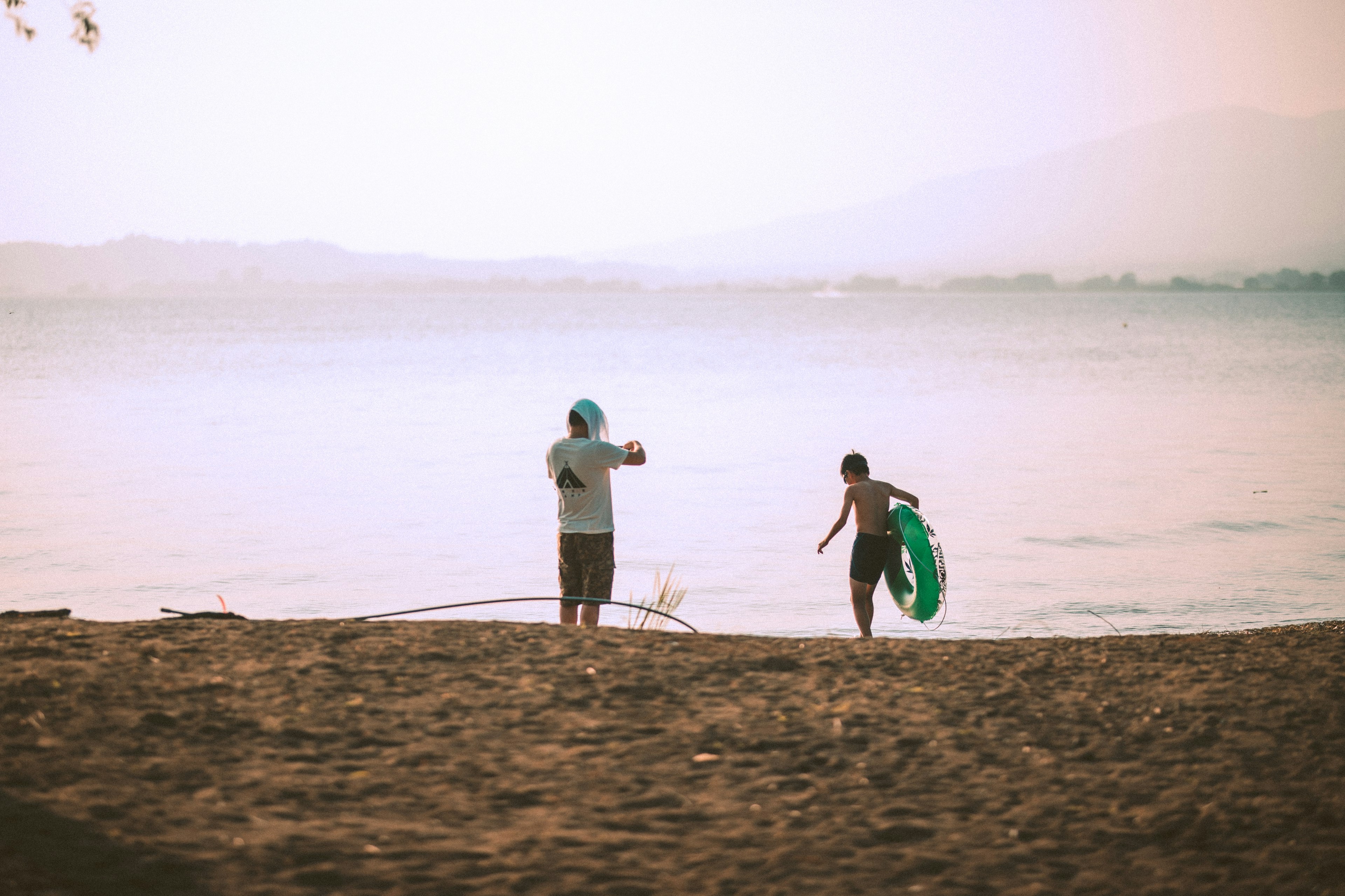 คนสองคนเล่นอยู่ที่ชายหาดแสงเย็นนุ่มนวล