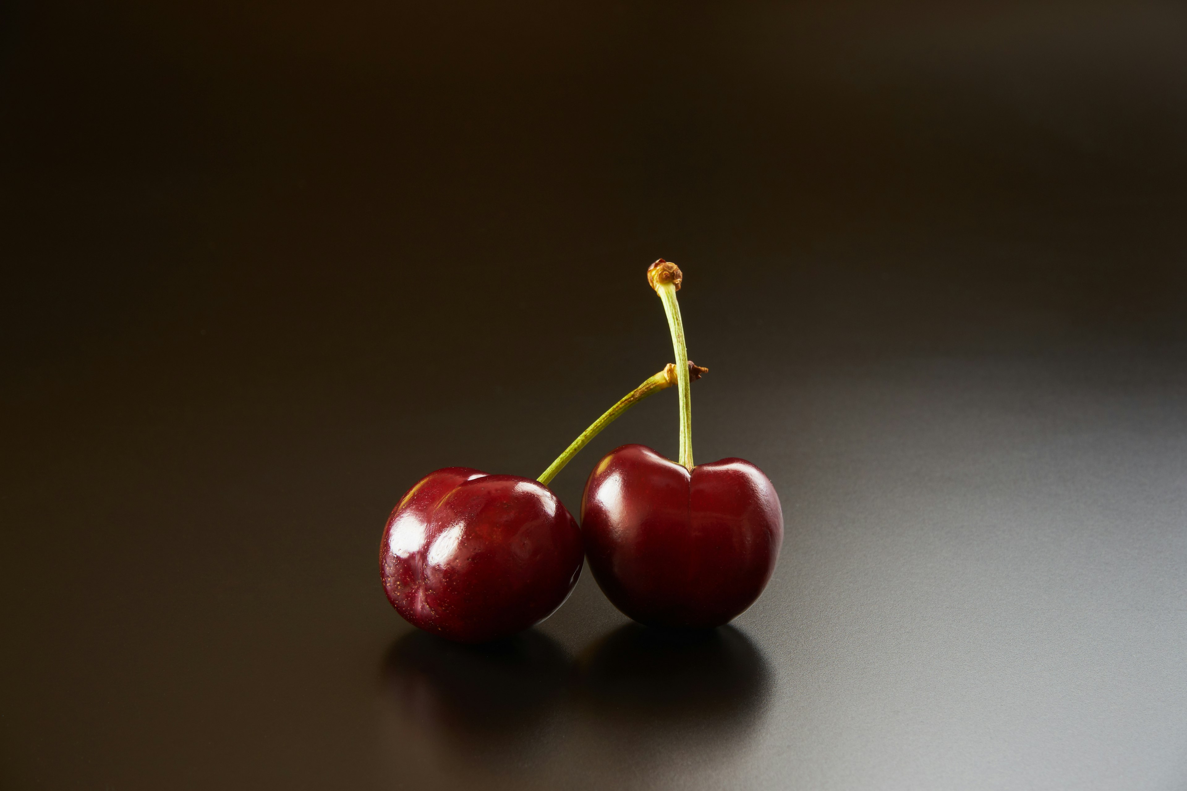 Dos cerezas rojas sobre un fondo negro