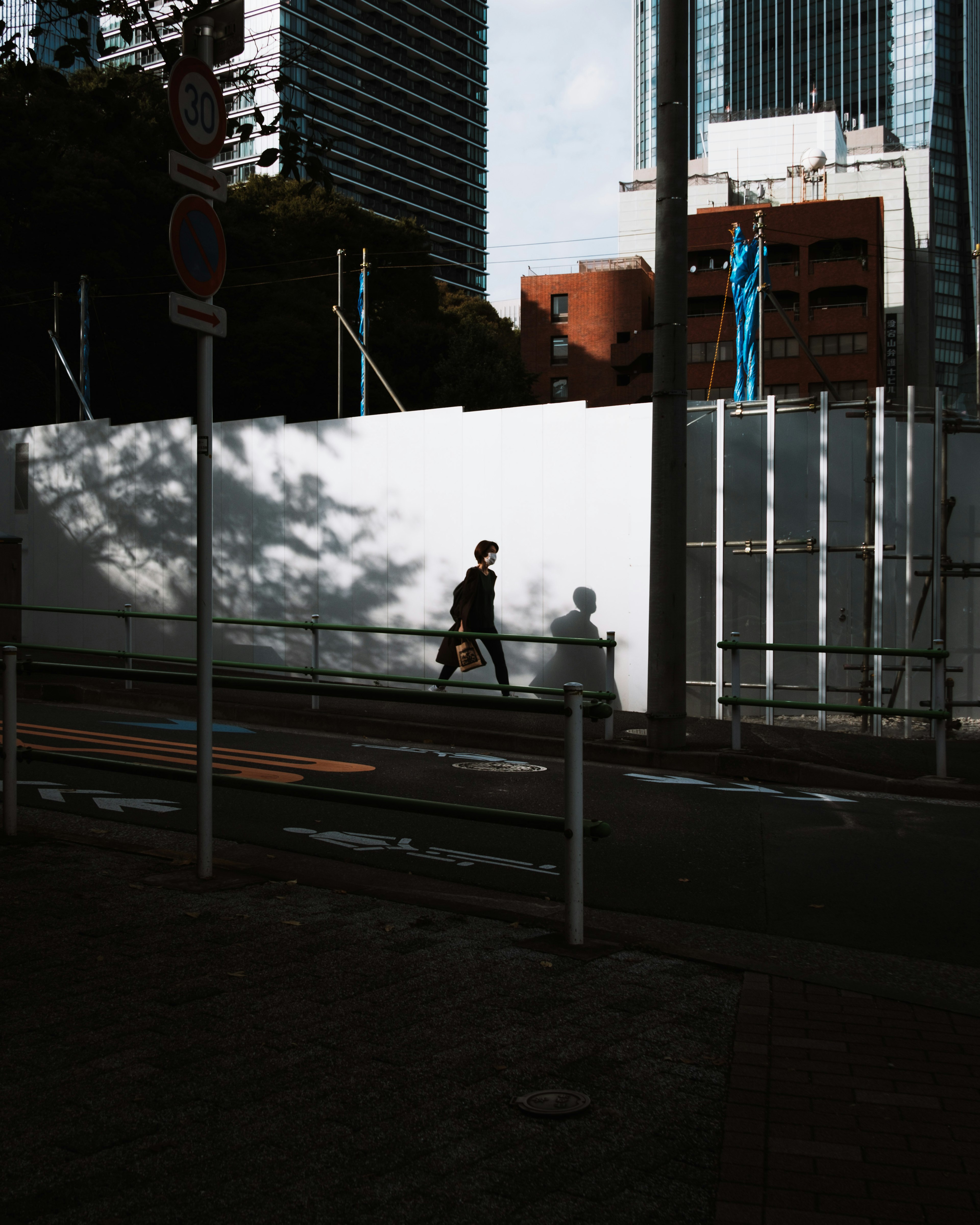 Urban scene with a person walking shadows and a white wall