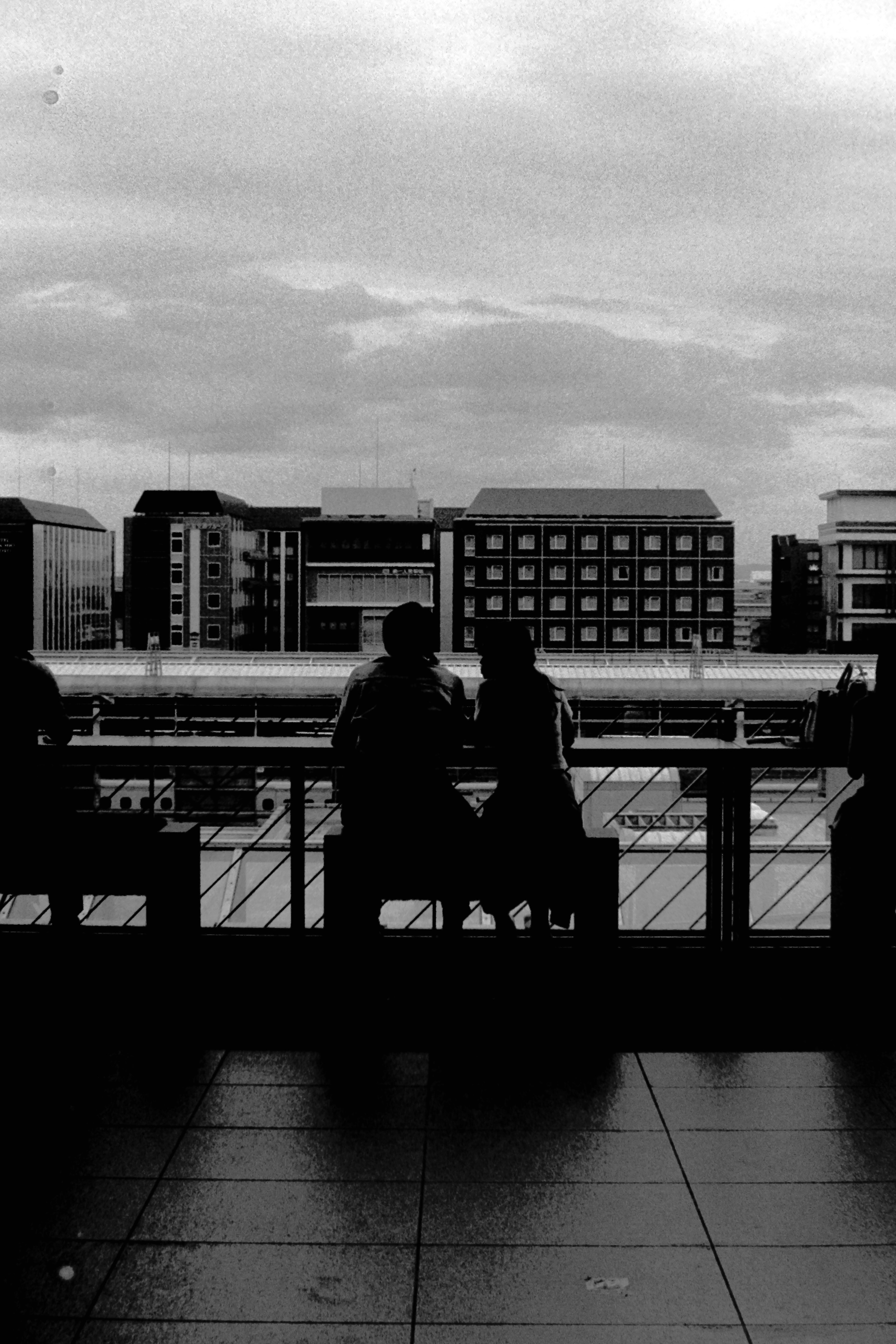 Figuras en silueta con vista a una escena fluvial en blanco y negro