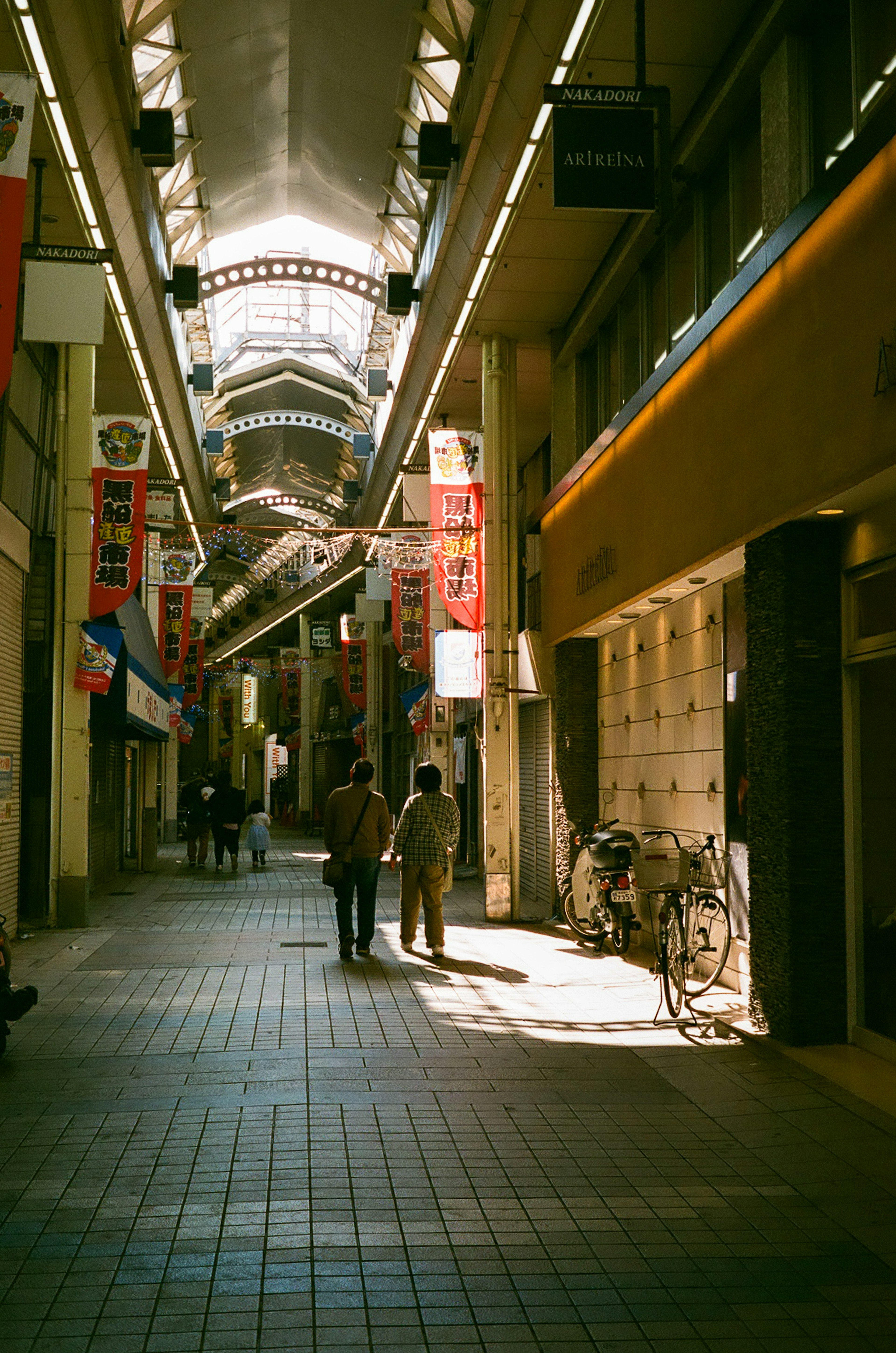 Bright arcade with people and bicycles