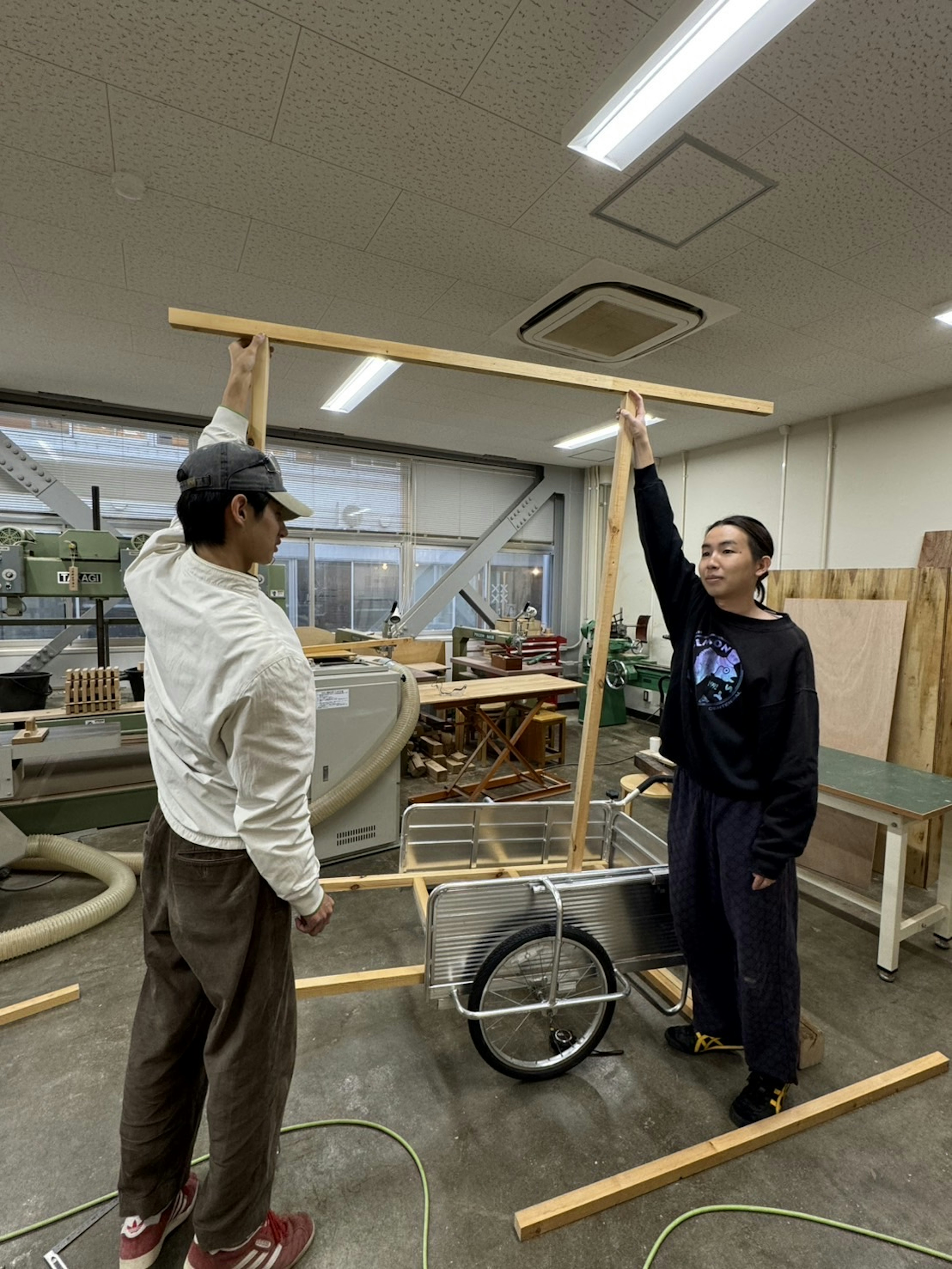 Dos personas ensamblando una estructura de madera en un taller