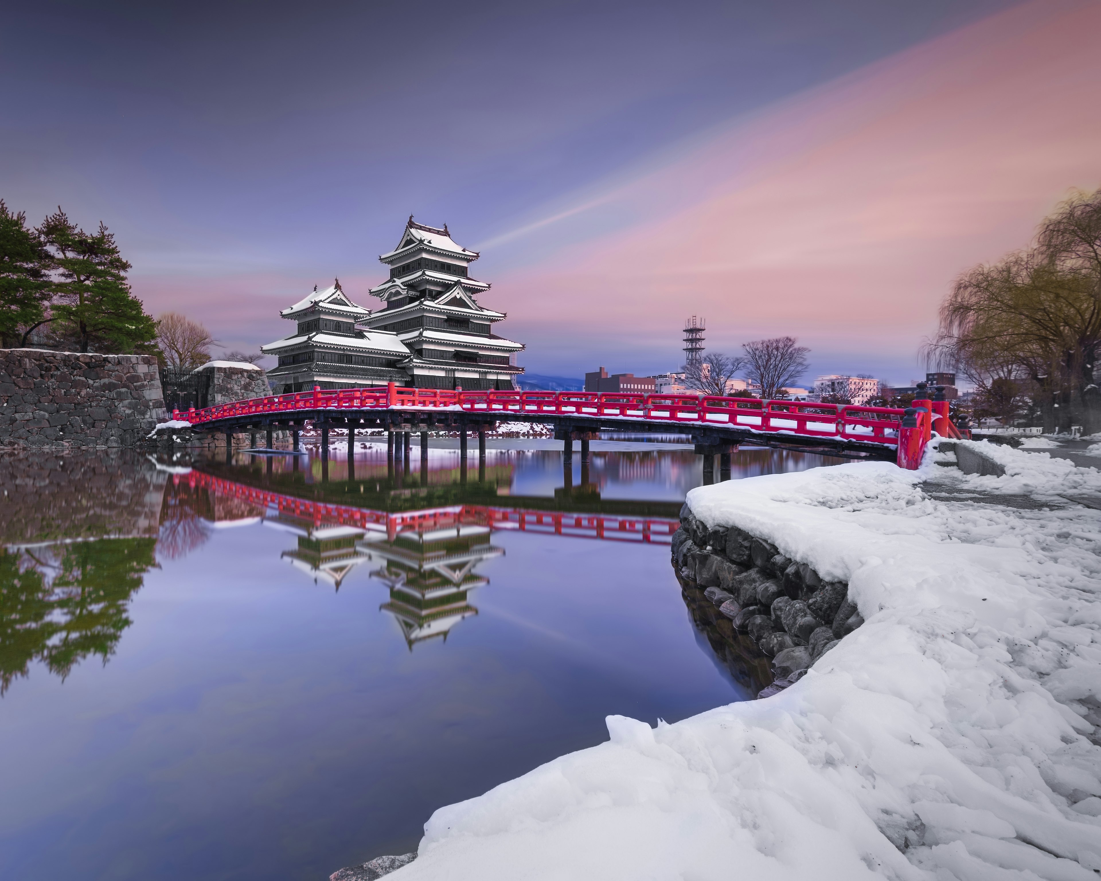 雪に覆われた松本城と赤い橋の美しい風景