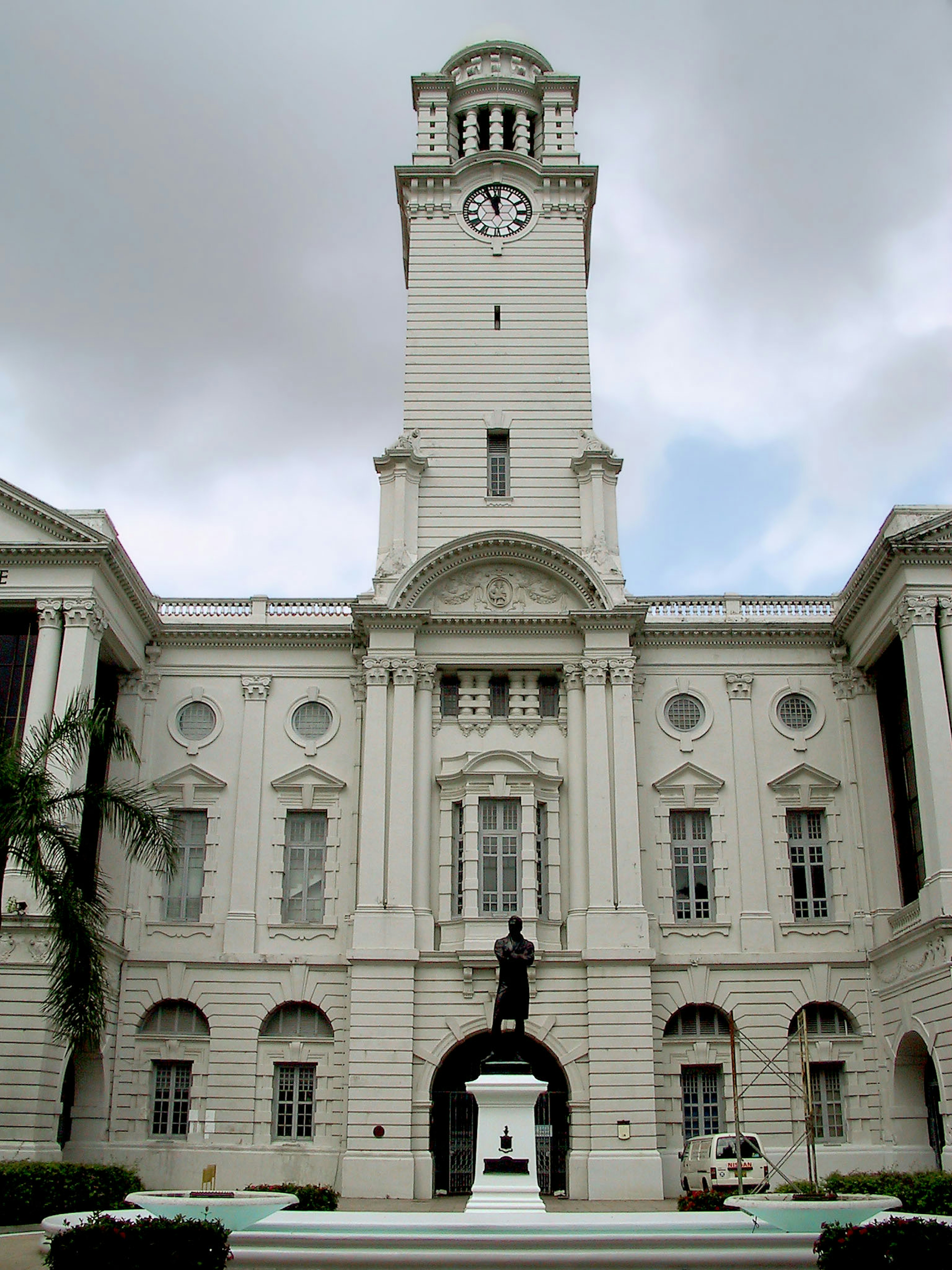 Edificio storico con torre dell'orologio e statua davanti