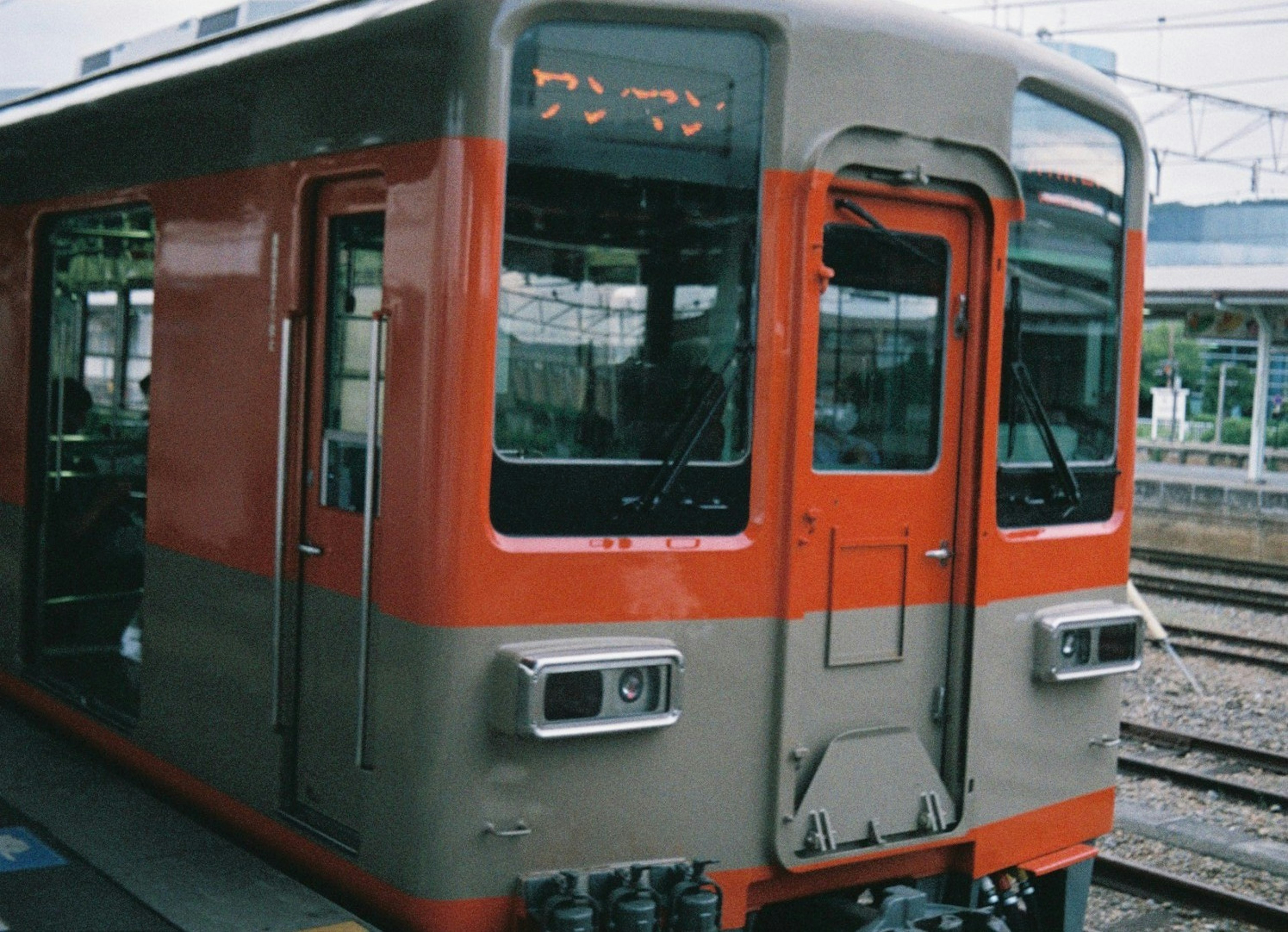 มุมมองด้านหน้าของรถไฟสีส้มและสีเทาที่สถานี