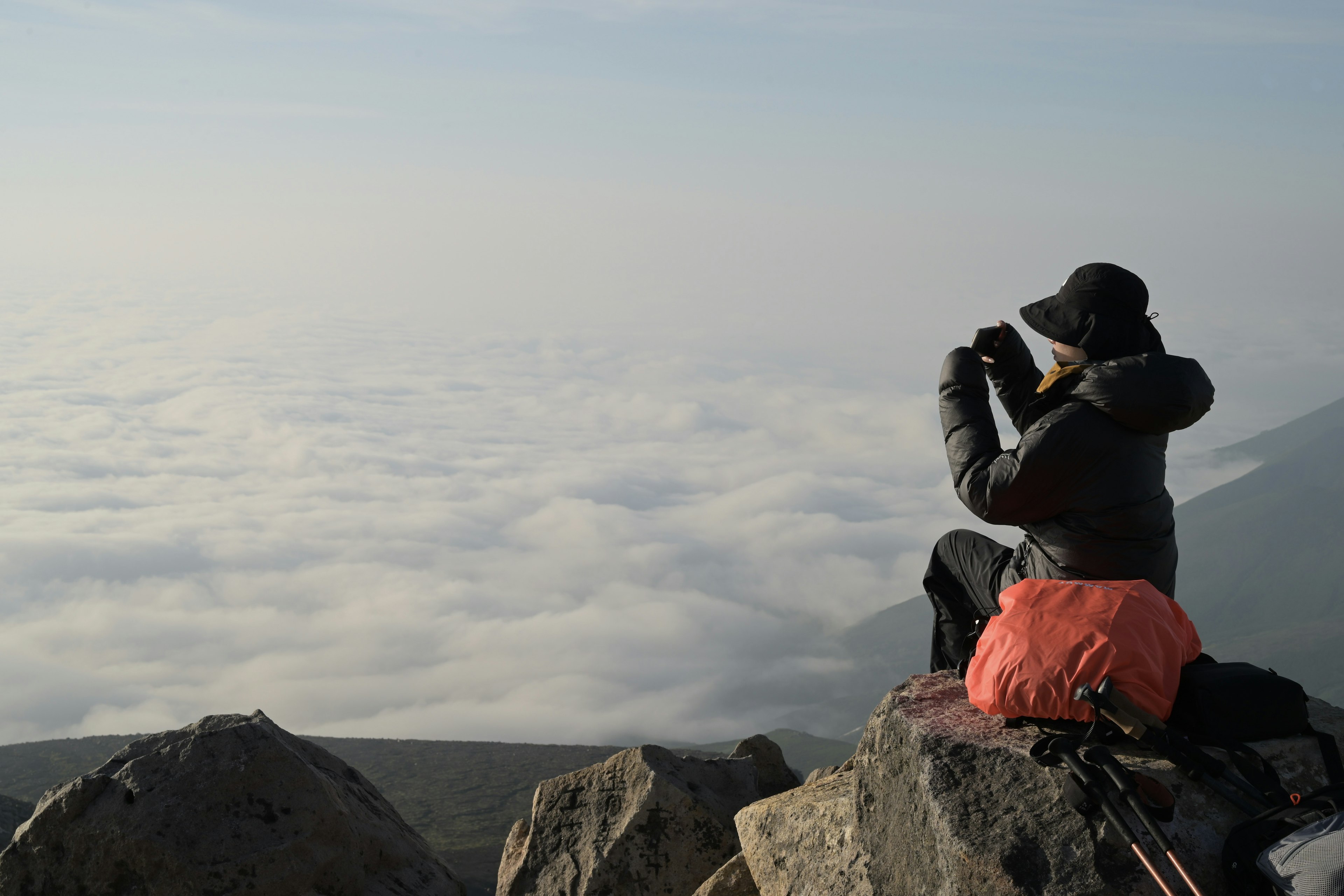 Escursionista che scatta una foto contro un mare di nuvole da una cima di montagna