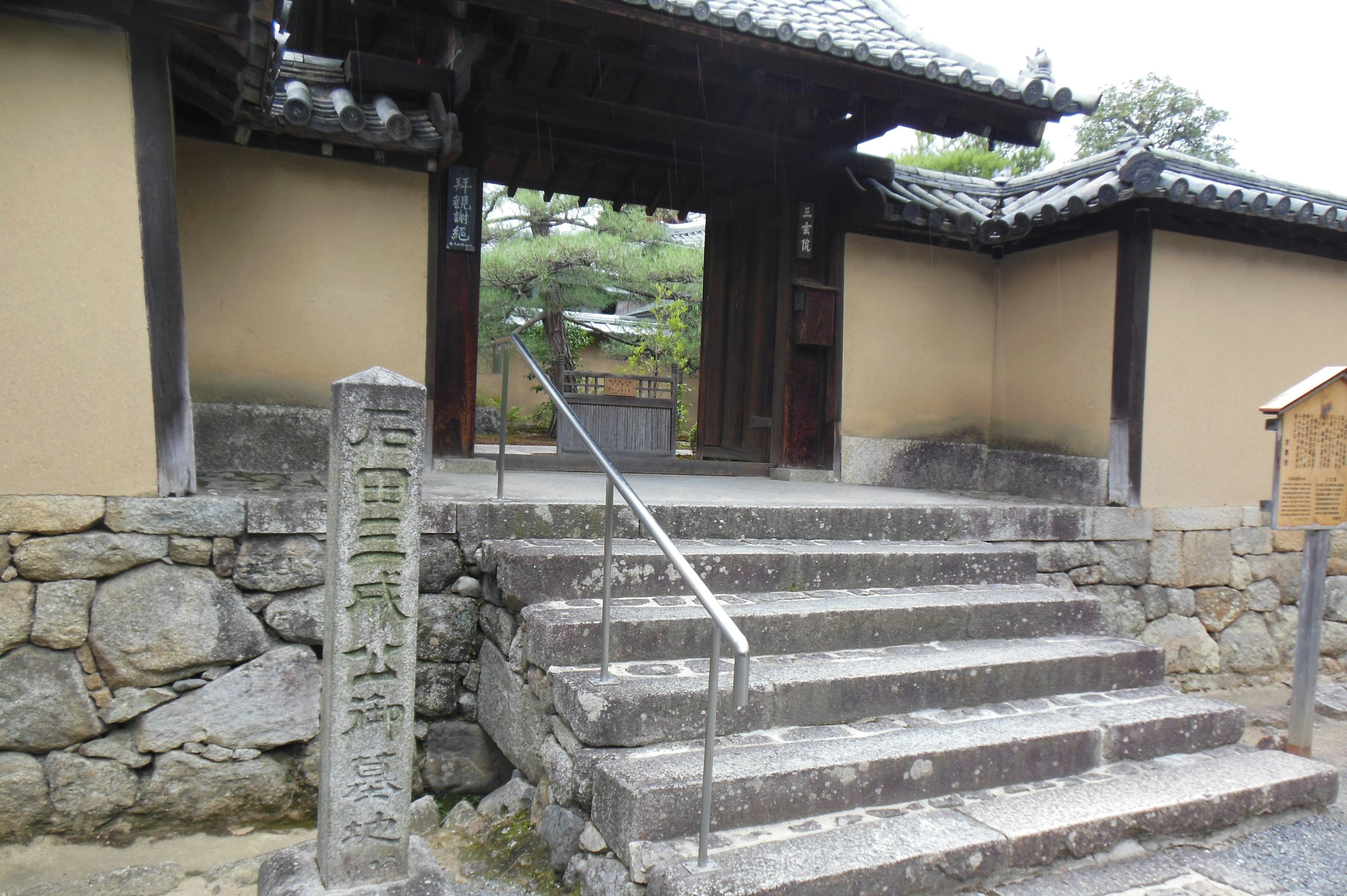 Stone steps leading to a traditional Japanese building entrance with a handrail