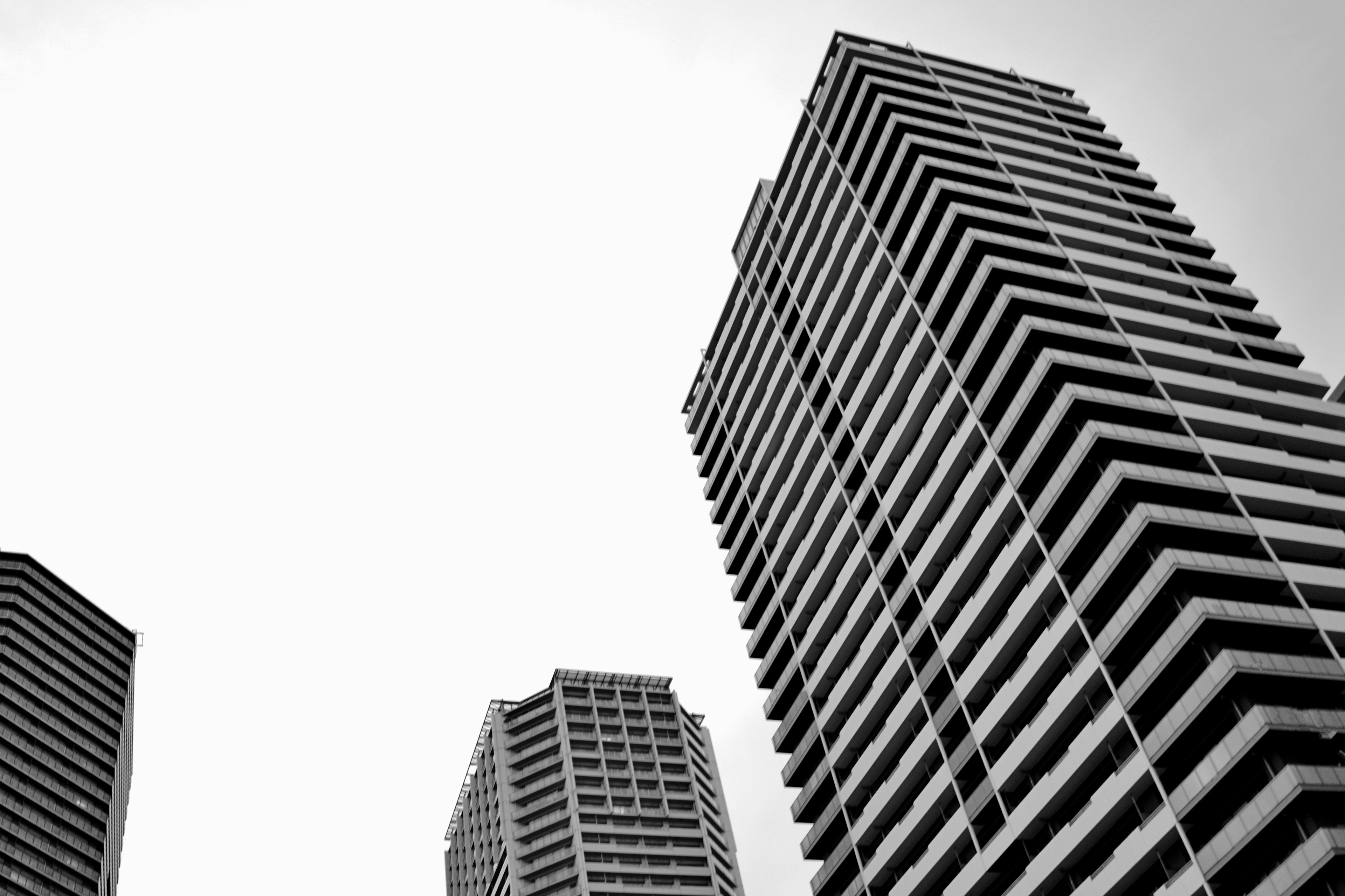 Foto hitam putih gedung pencakar langit diambil dari sudut rendah menyoroti balkon bertingkat