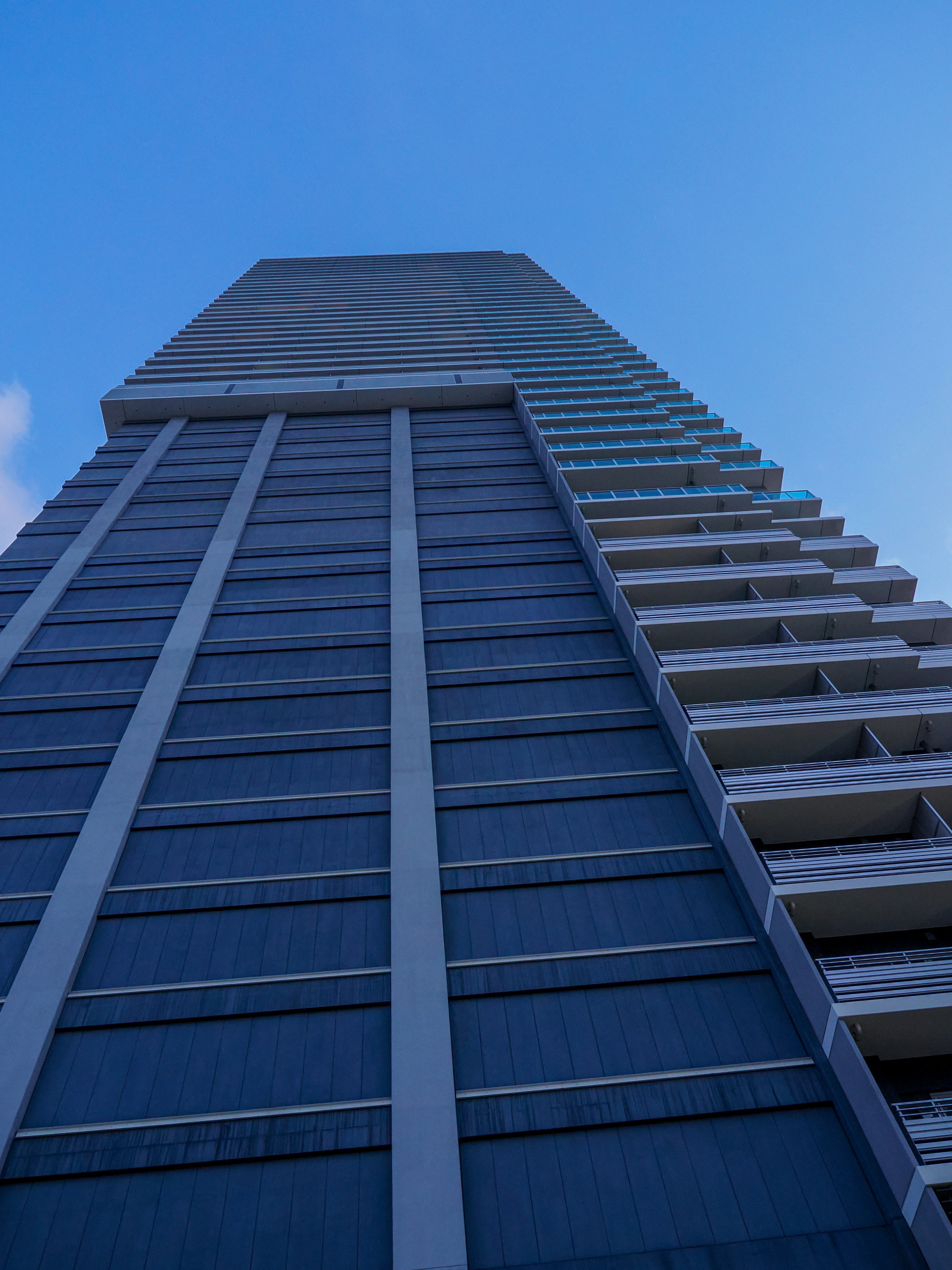 Ein Foto eines hohen Gebäudes von unten unter einem blauen Himmel mit einer blauen Fassade