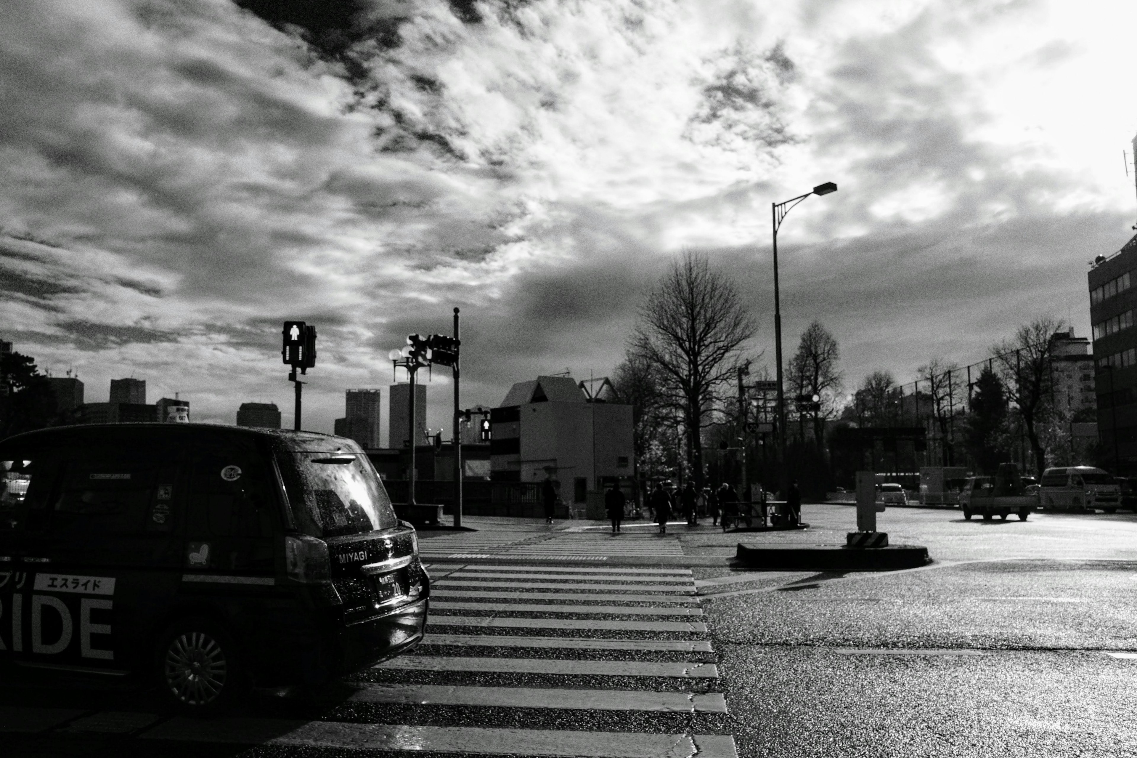 Taxi stopped at a crosswalk with a cloudy sky in black and white