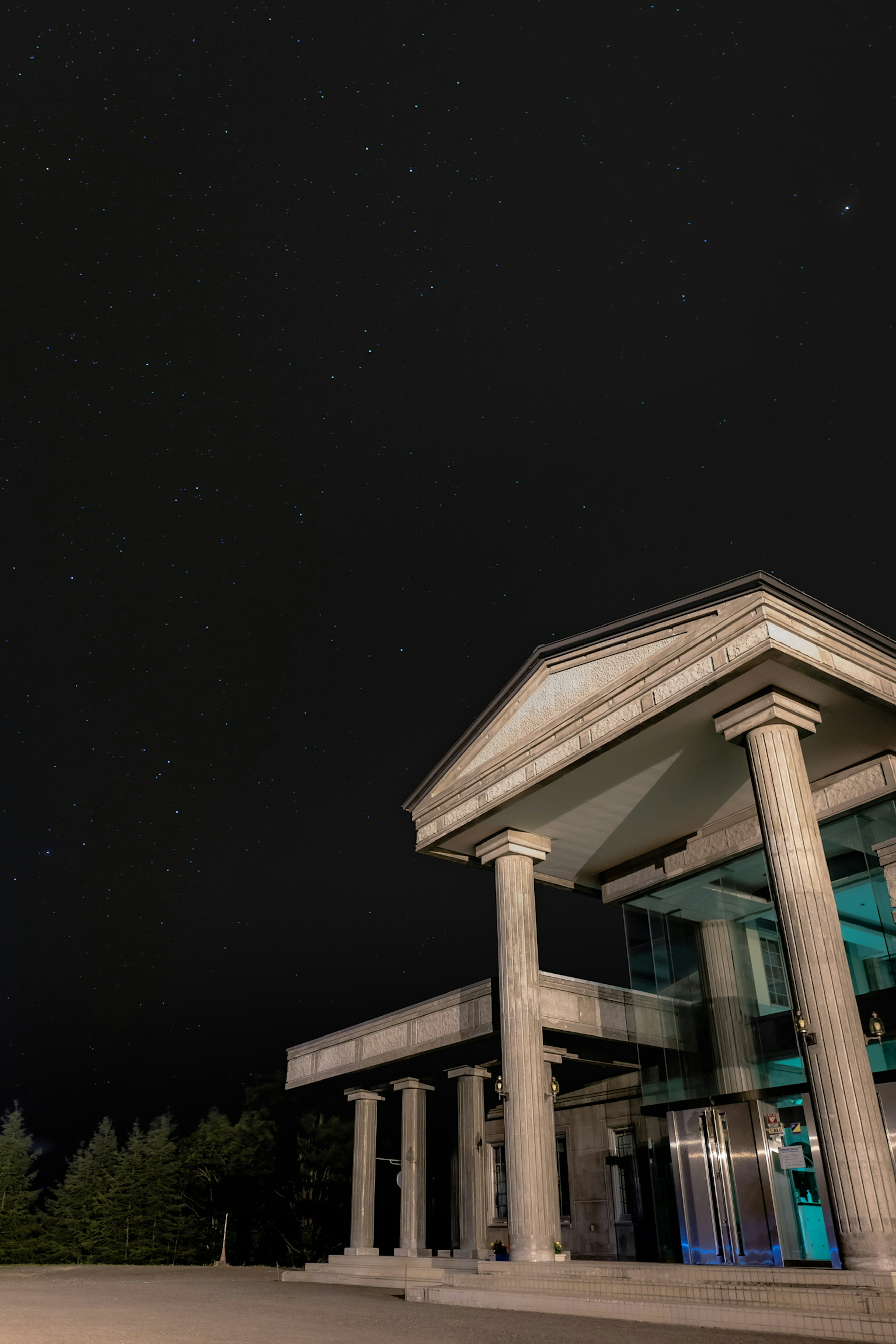 Exterior de un edificio moderno con columnas bajo un cielo estrellado