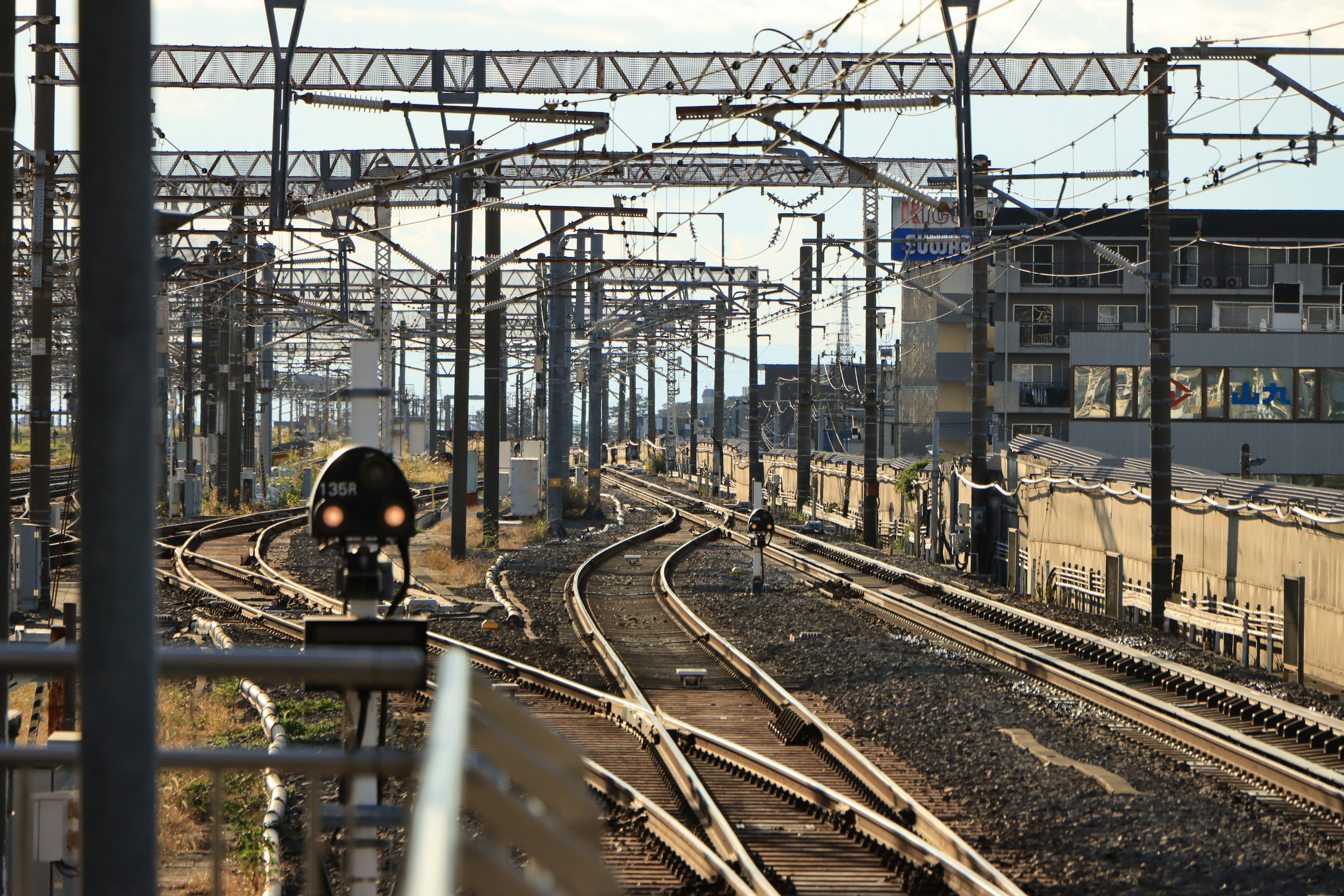 Pistes de chemin de fer avec un train qui arrive, lignes droites et courbes, gare à proximité