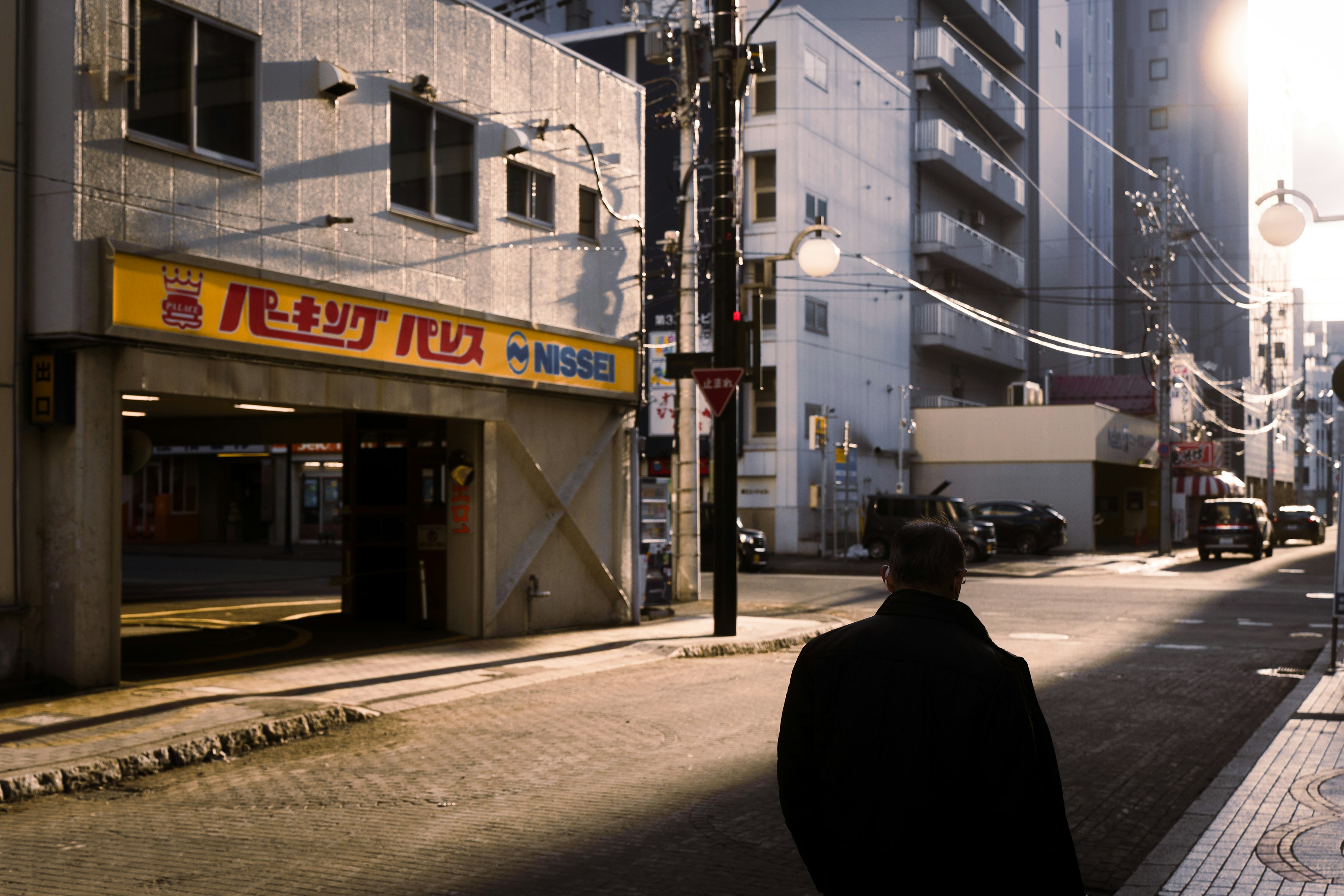 A man walking on a dimly lit street with buildings in the background