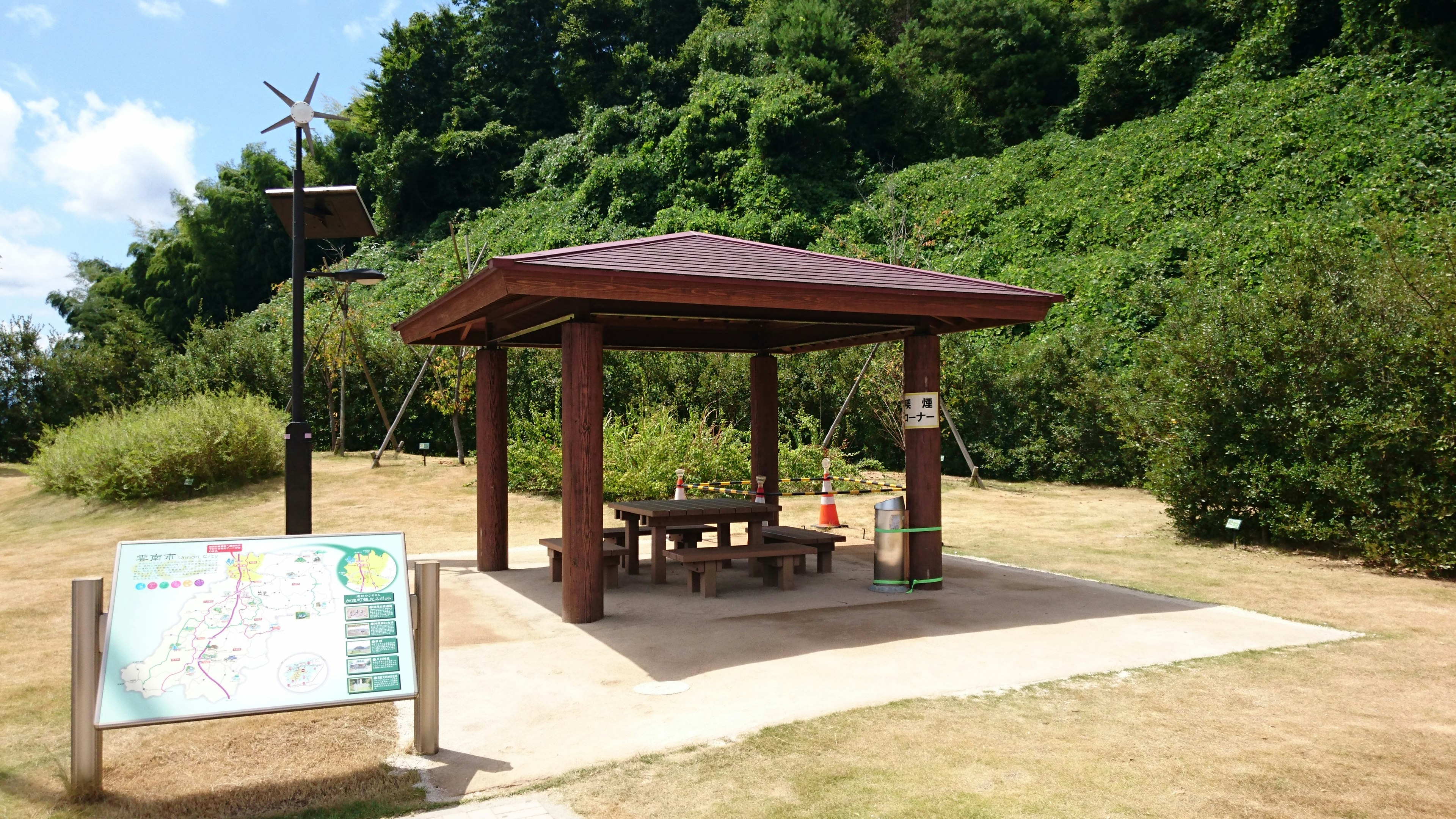 Un área de descanso con sombra, una mesa de picnic y un mapa cercano