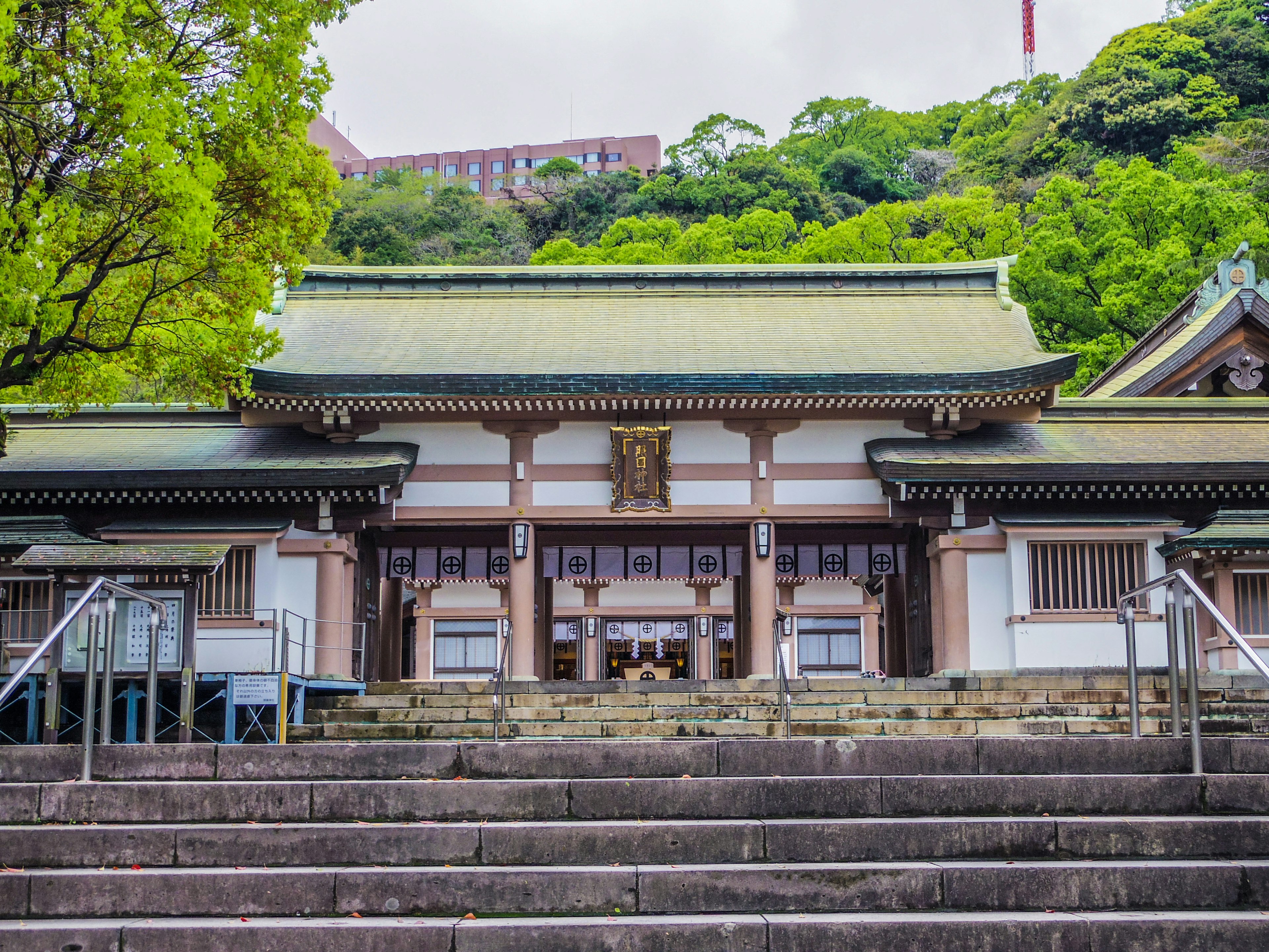 Front entrance of a traditional Japanese shrine surrounded by lush greenery