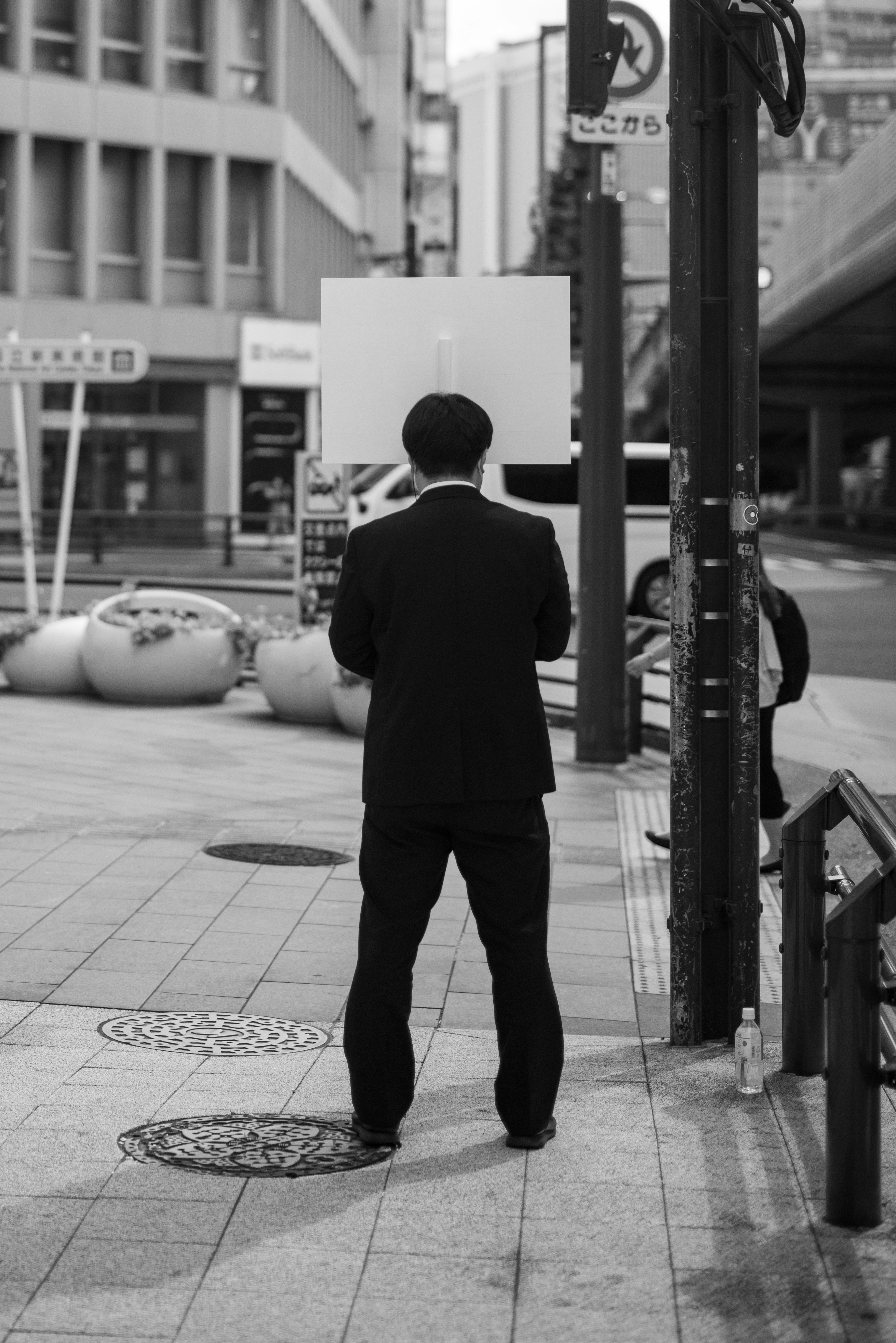 A man in a black suit standing at a street corner