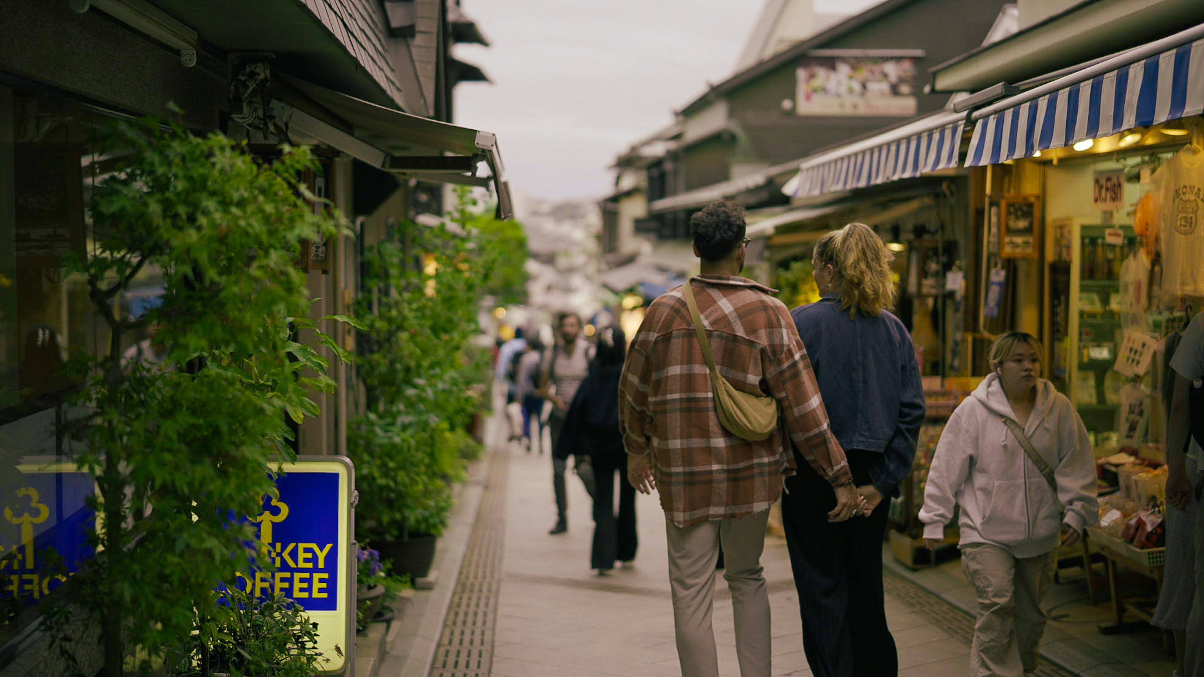 Couple walking hand in hand down a lively street lined with cafes and shops