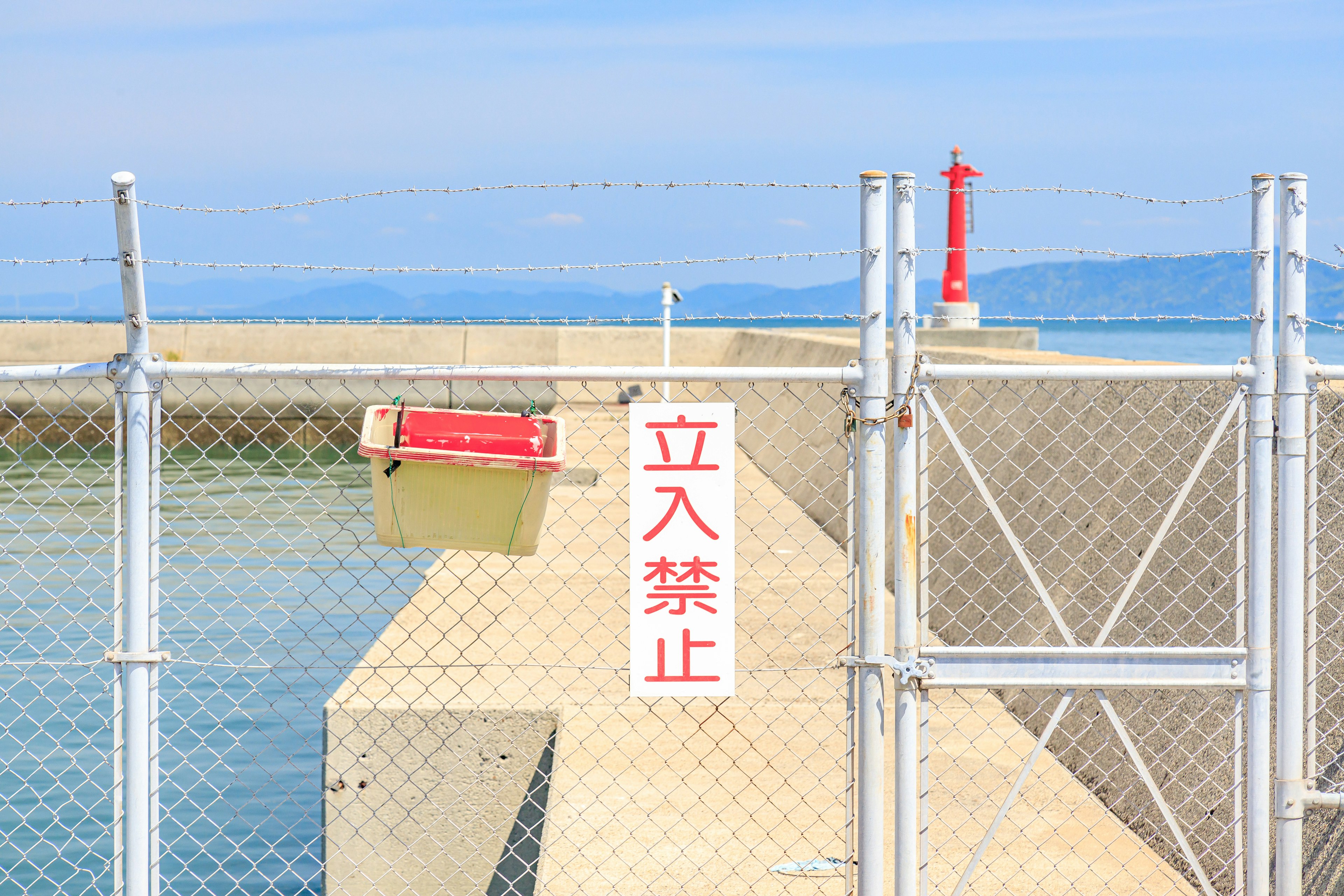 Fence with no entry sign and breakwater in the background