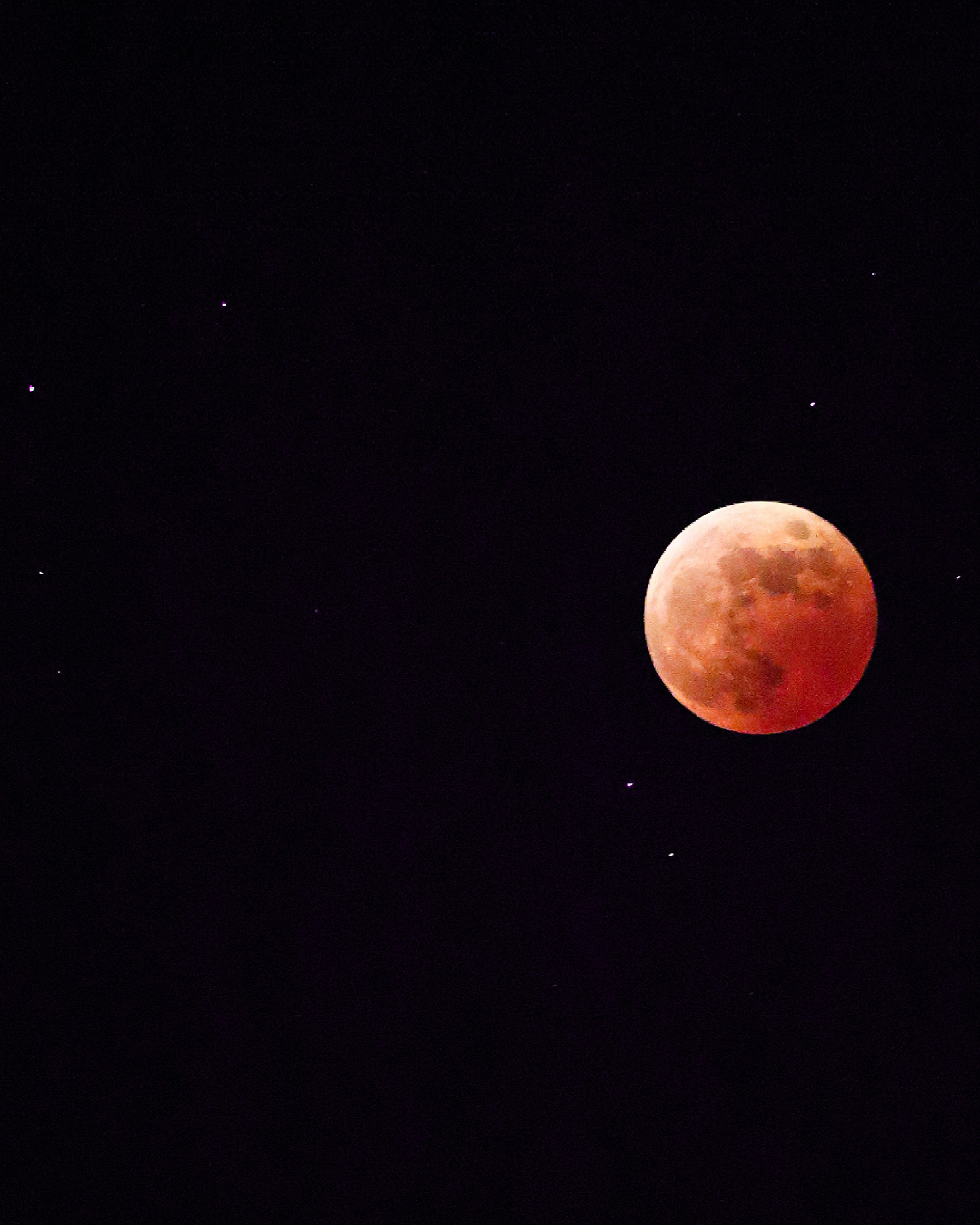 Red moon surrounded by stars in a dark night sky