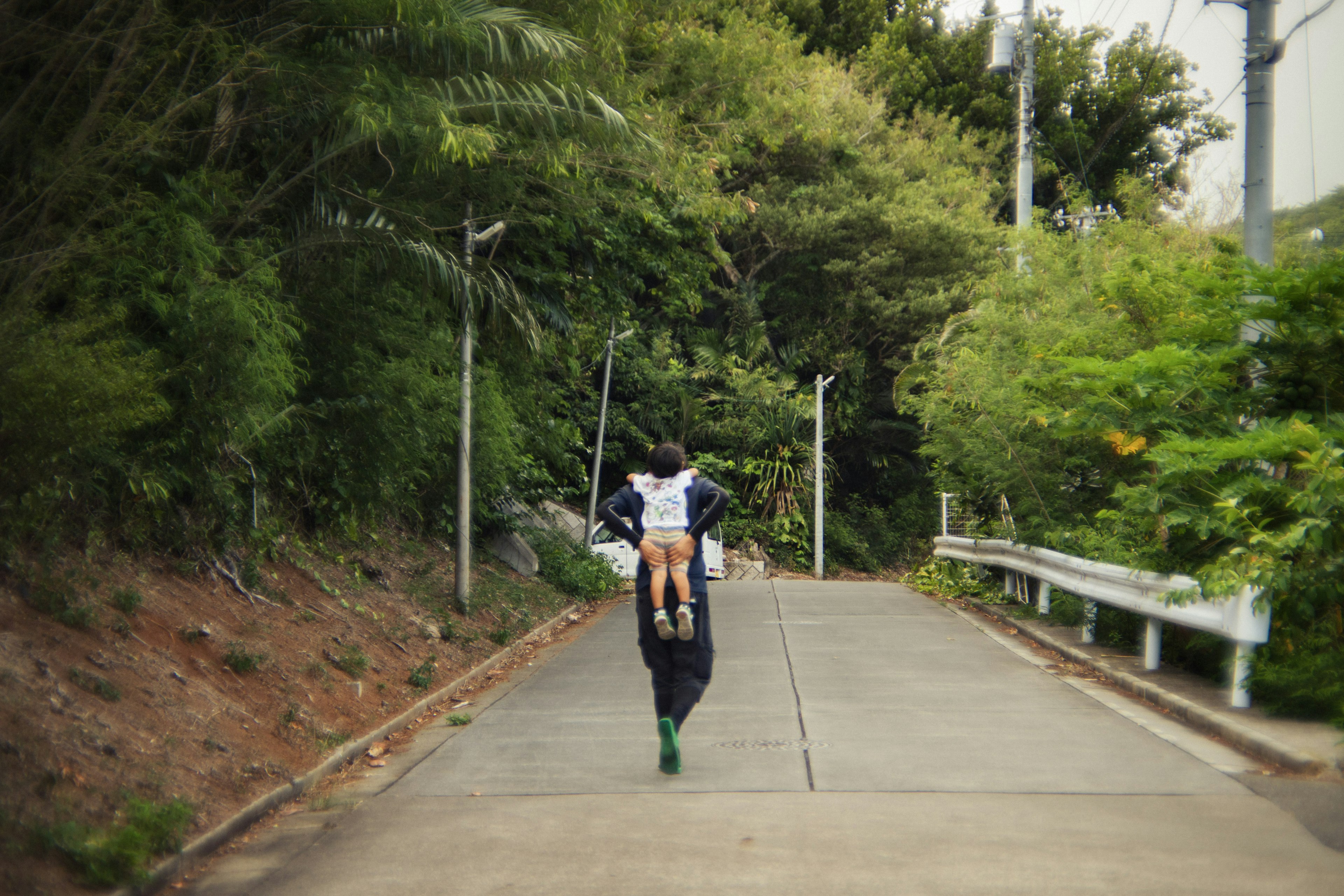 緑に囲まれた道を歩く人