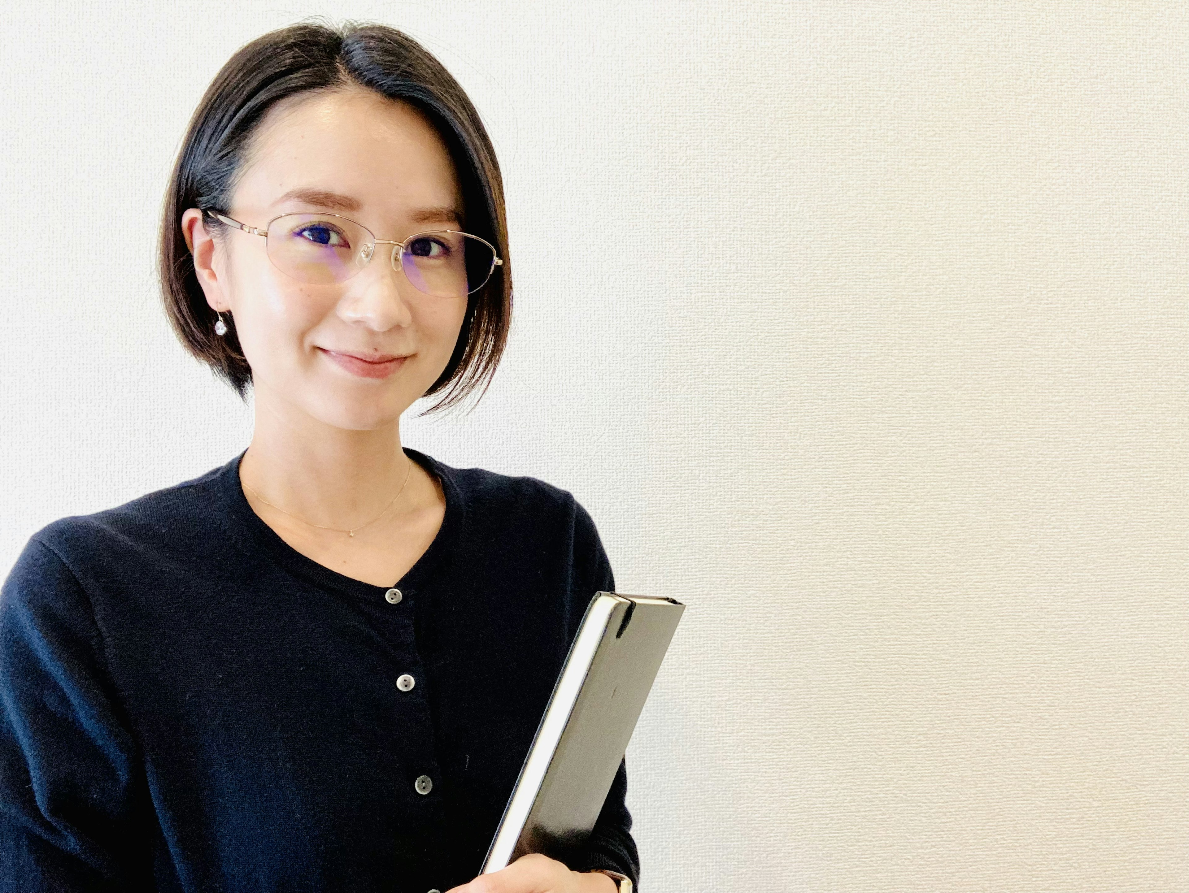 A woman in a black cardigan smiling while holding a tablet