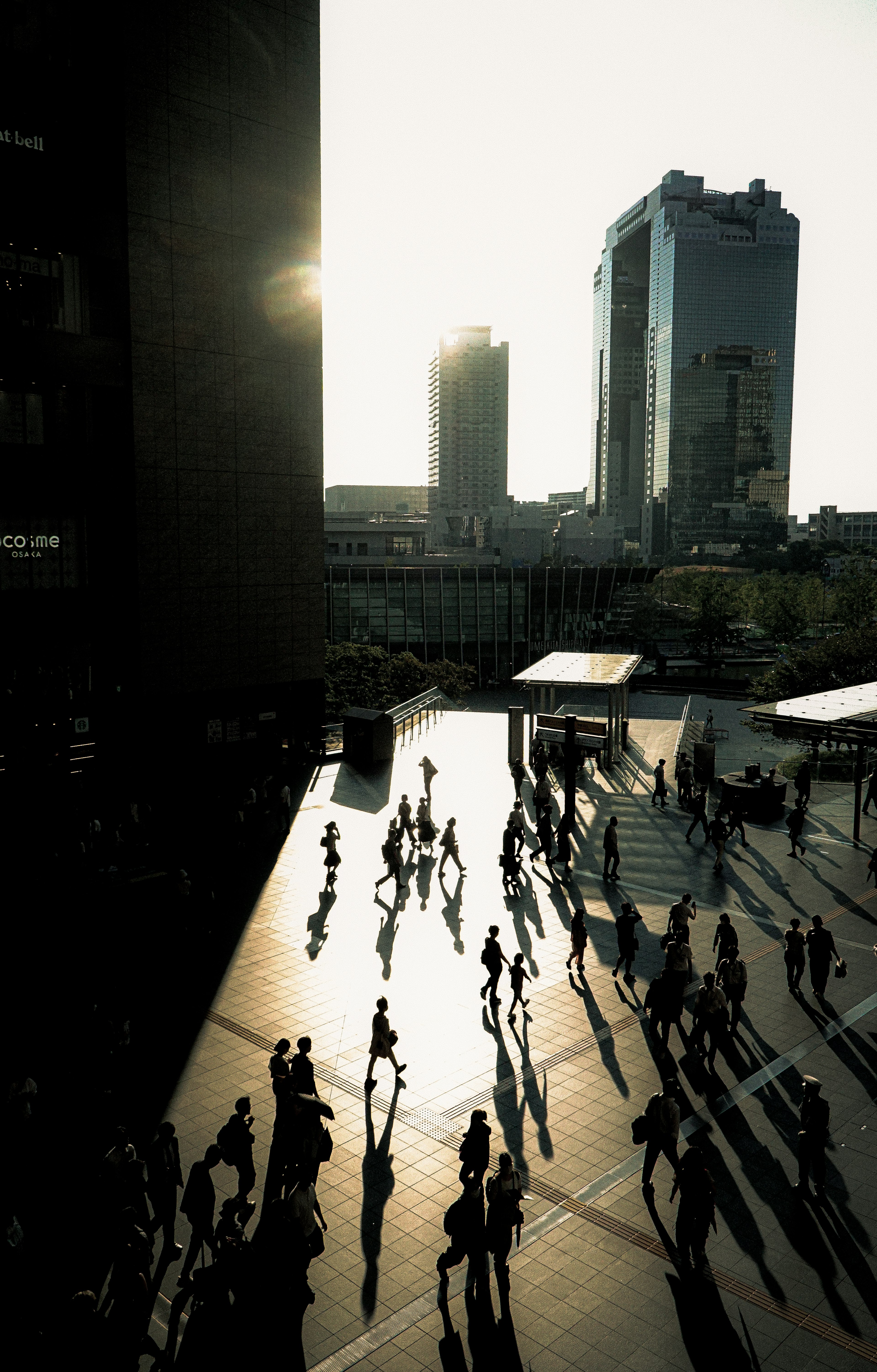 Scène urbaine avec des personnes marchant et des ombres longues au coucher du soleil