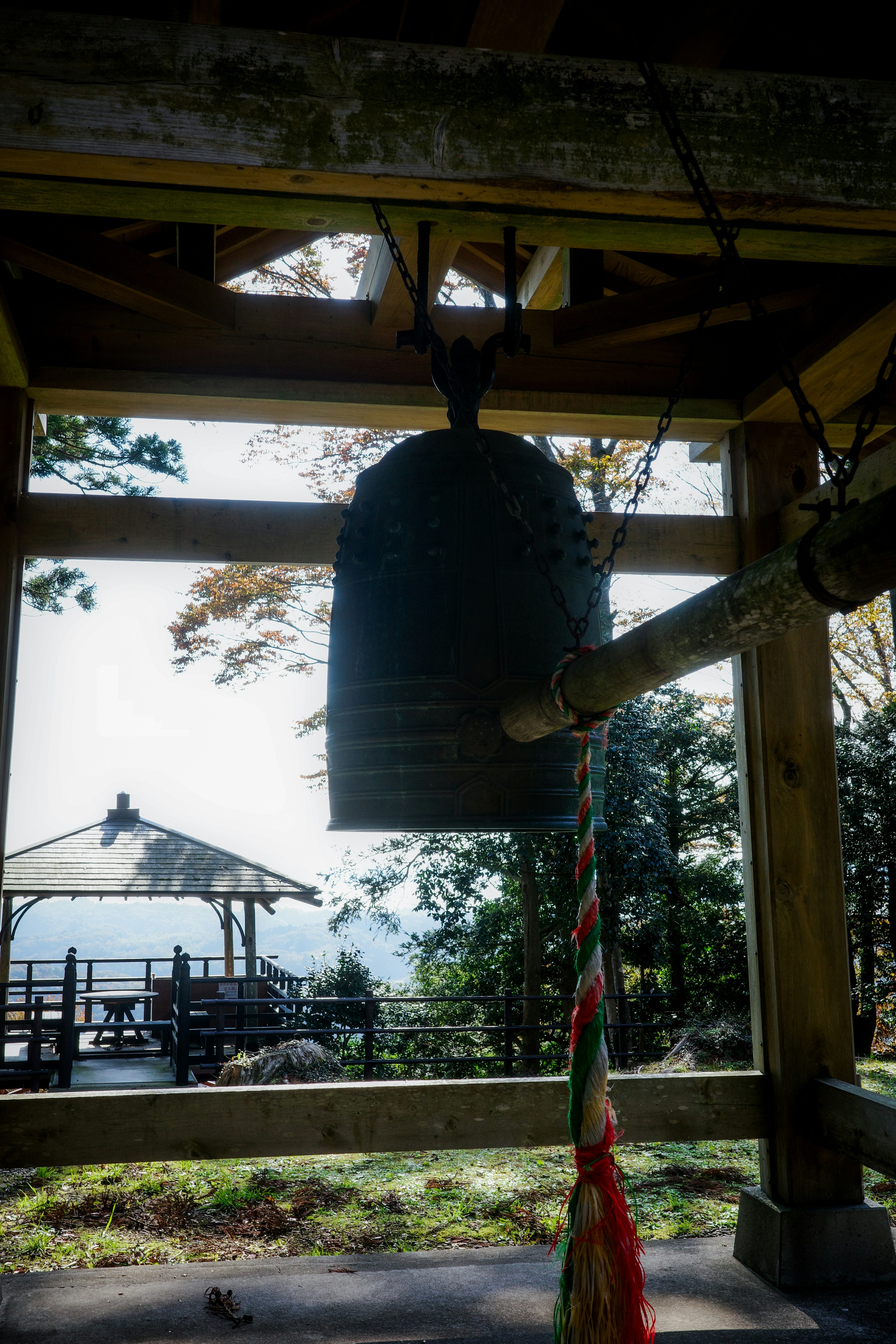 鐘が吊るされた木製の構造物の内部からの眺め 自然の景色が背景に広がる