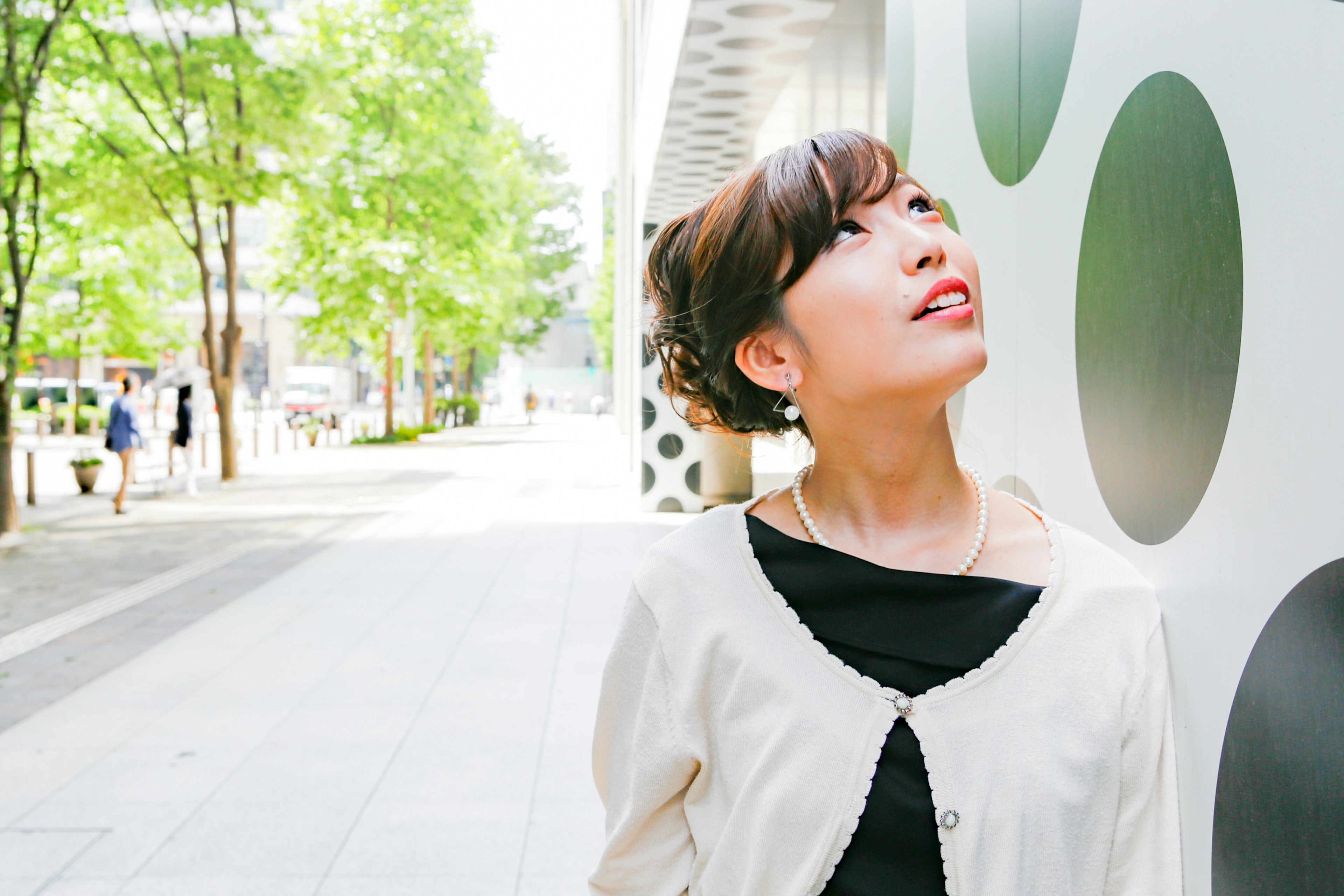 A woman looking up at a wall with green trees in the background