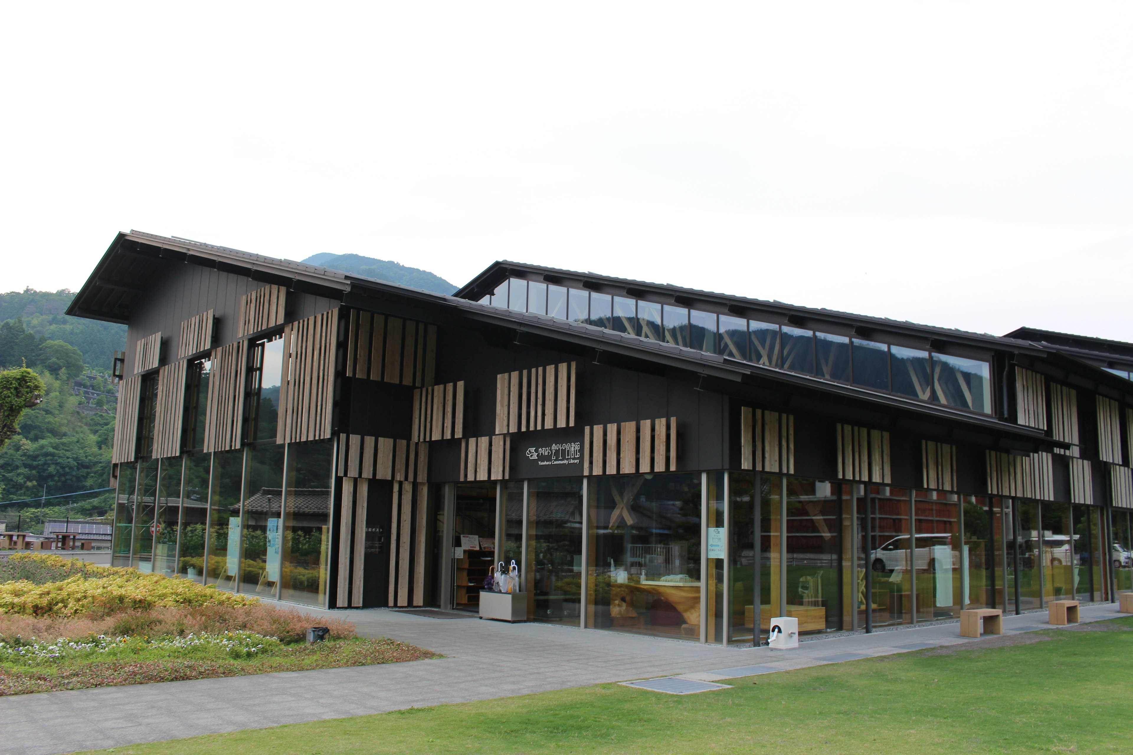 Modern architectural facade with wooden elements green lawn and surrounding mountains