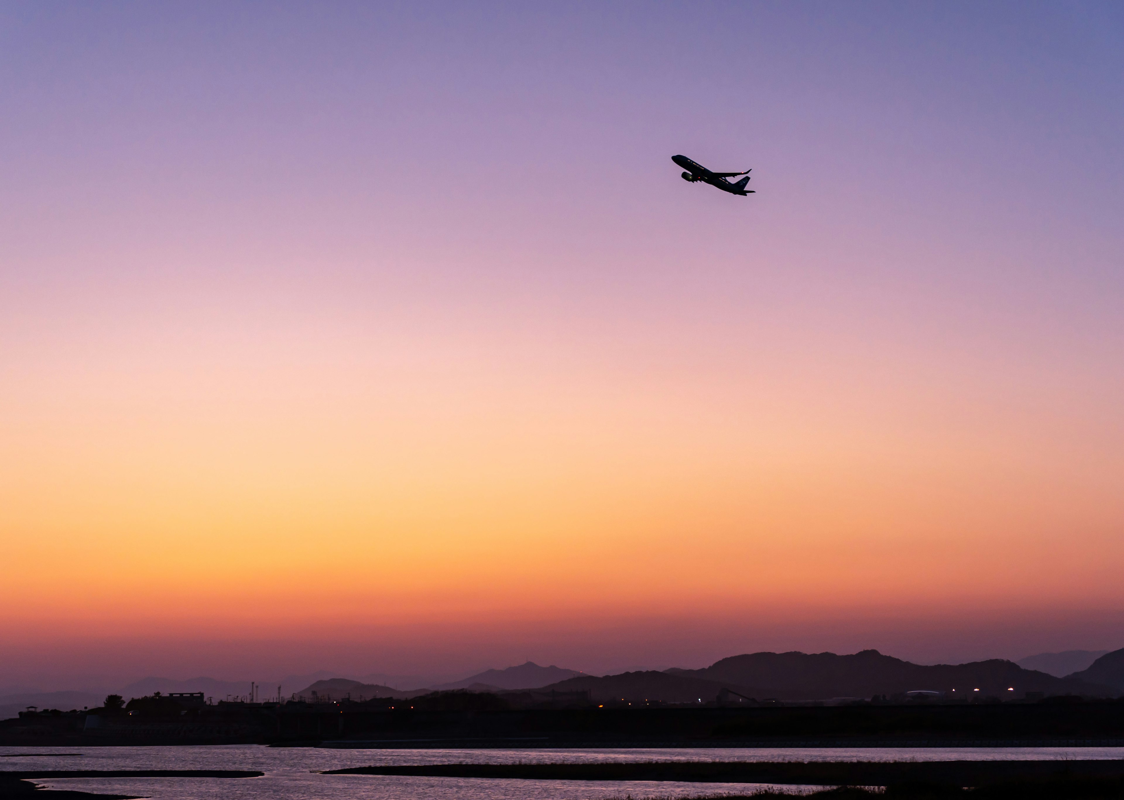 夕焼けの空に飛行機が飛び立つシーン