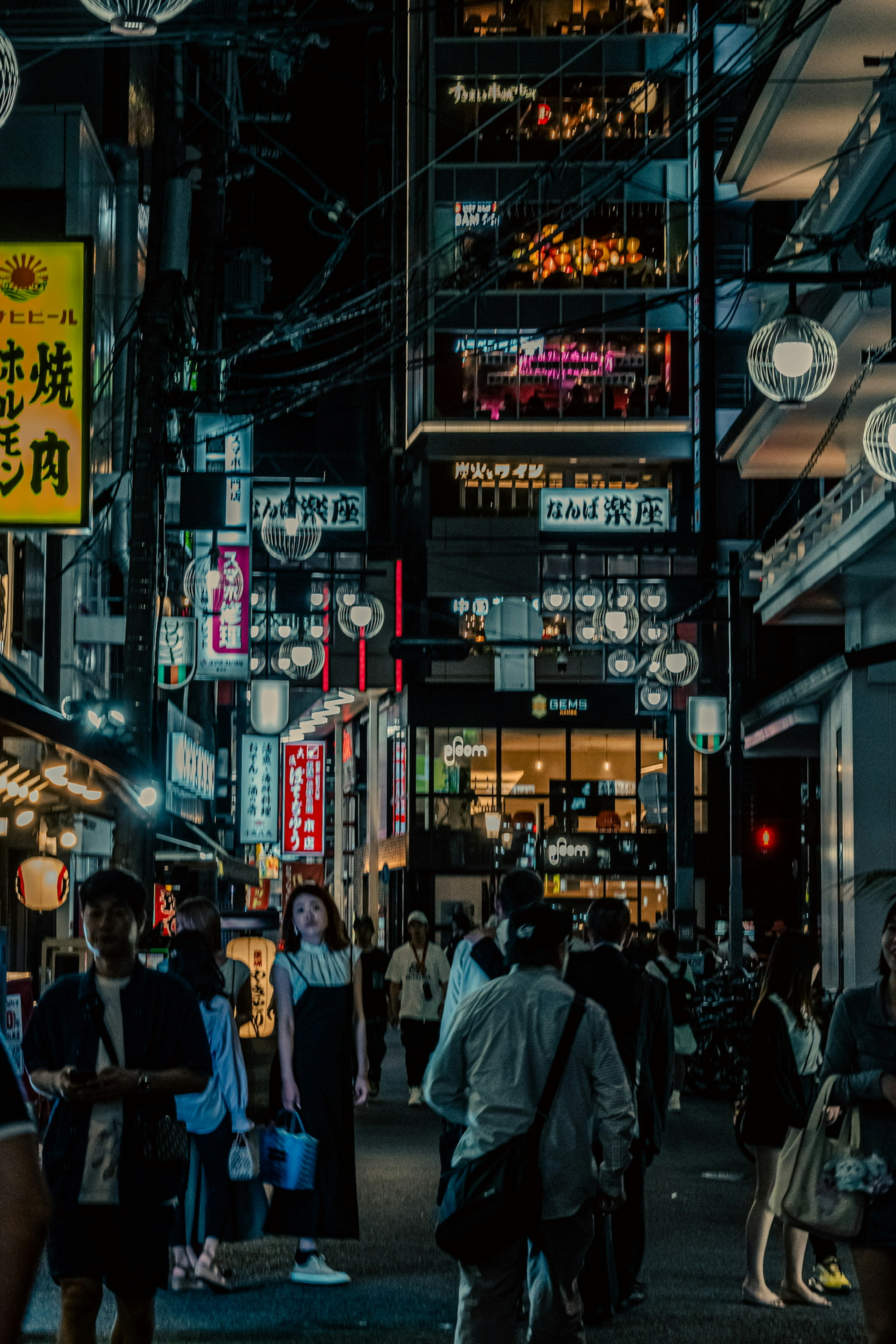 Pemandangan jalan yang ramai di Tokyo pada malam hari dengan tanda neon yang cerah dan kerumunan orang