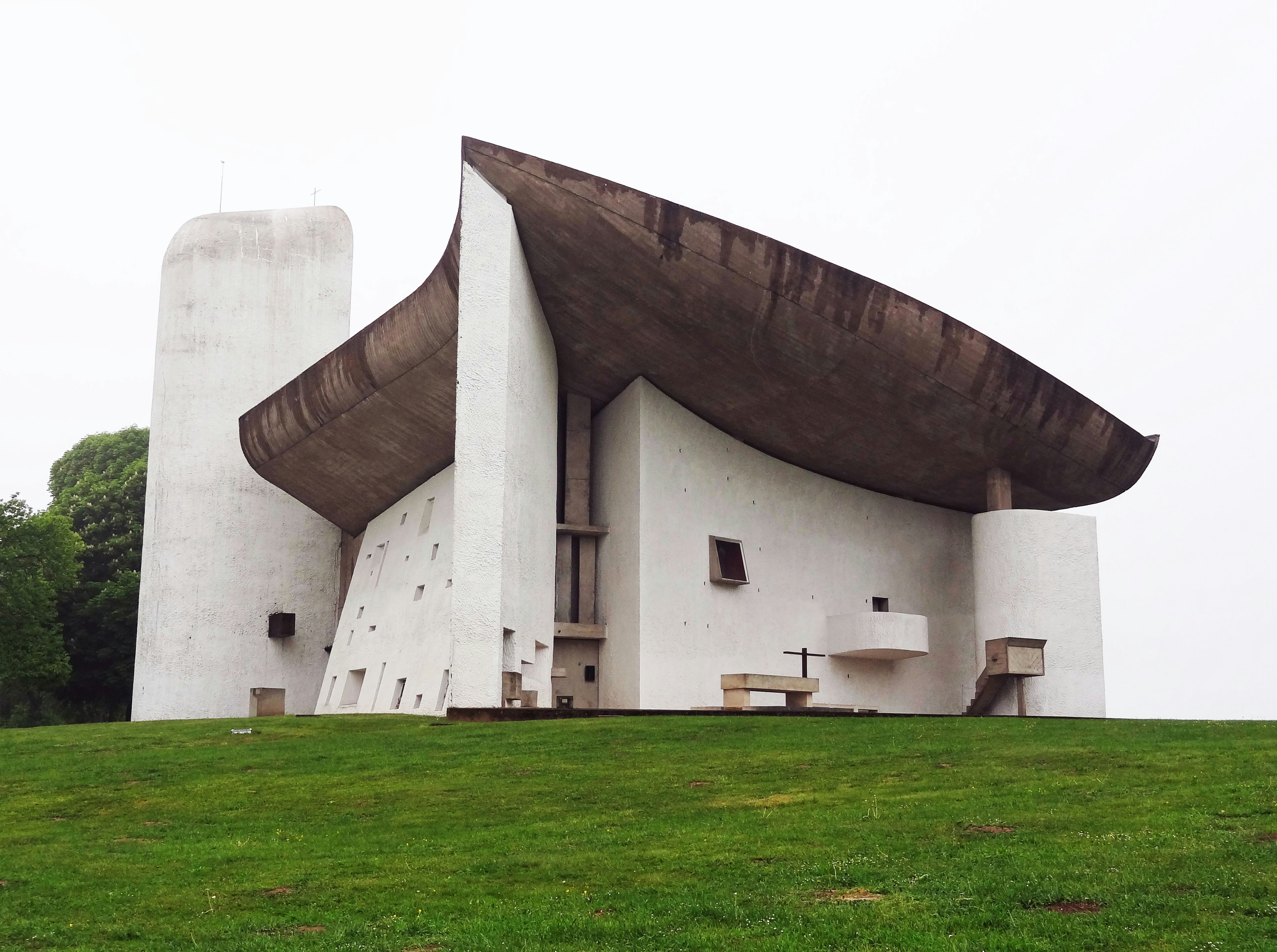 Iglesia de concreto blanco diseñada por Le Corbusier situada sobre un césped verde