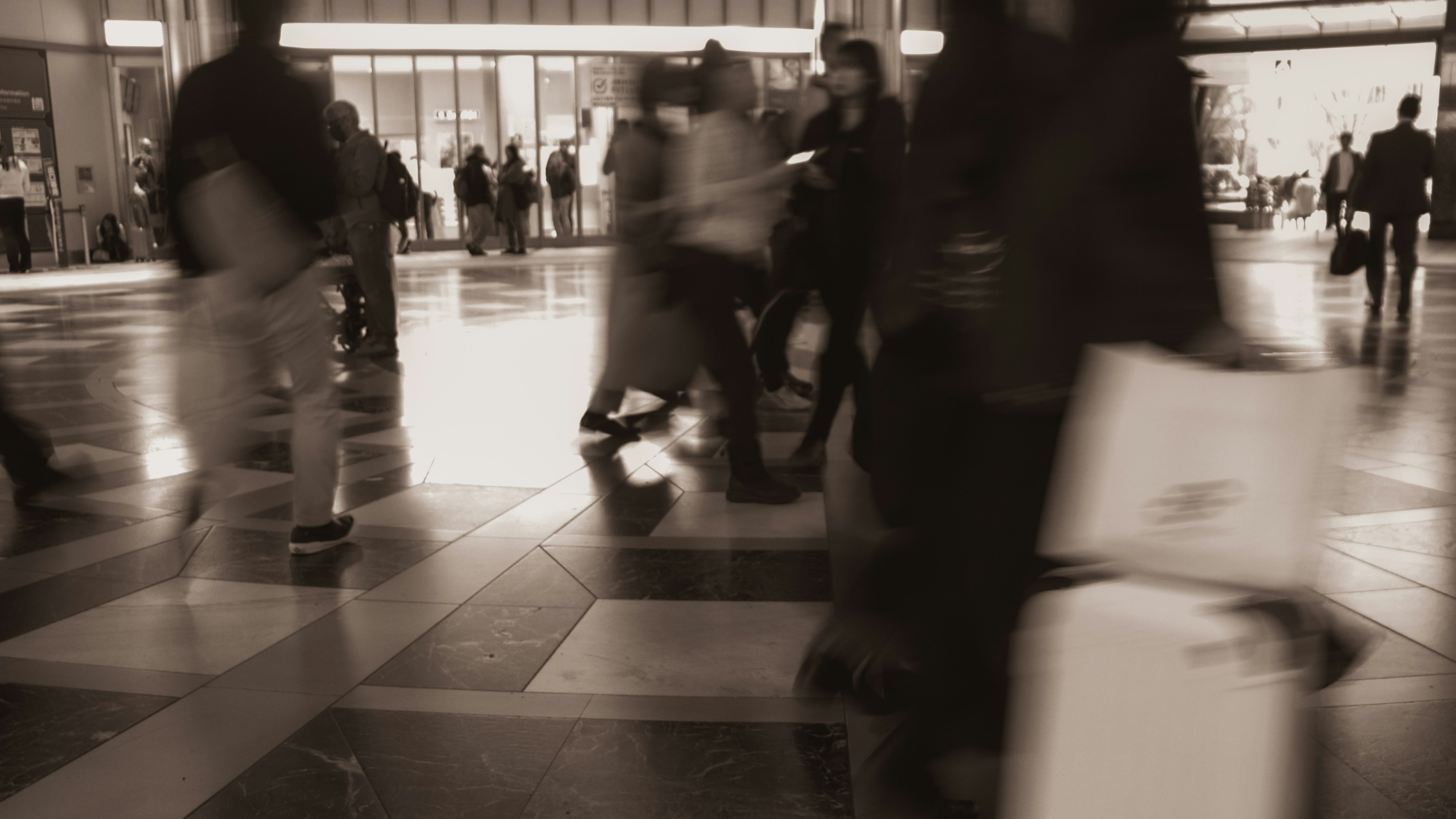 Busy scene of people walking in a train station in monochrome