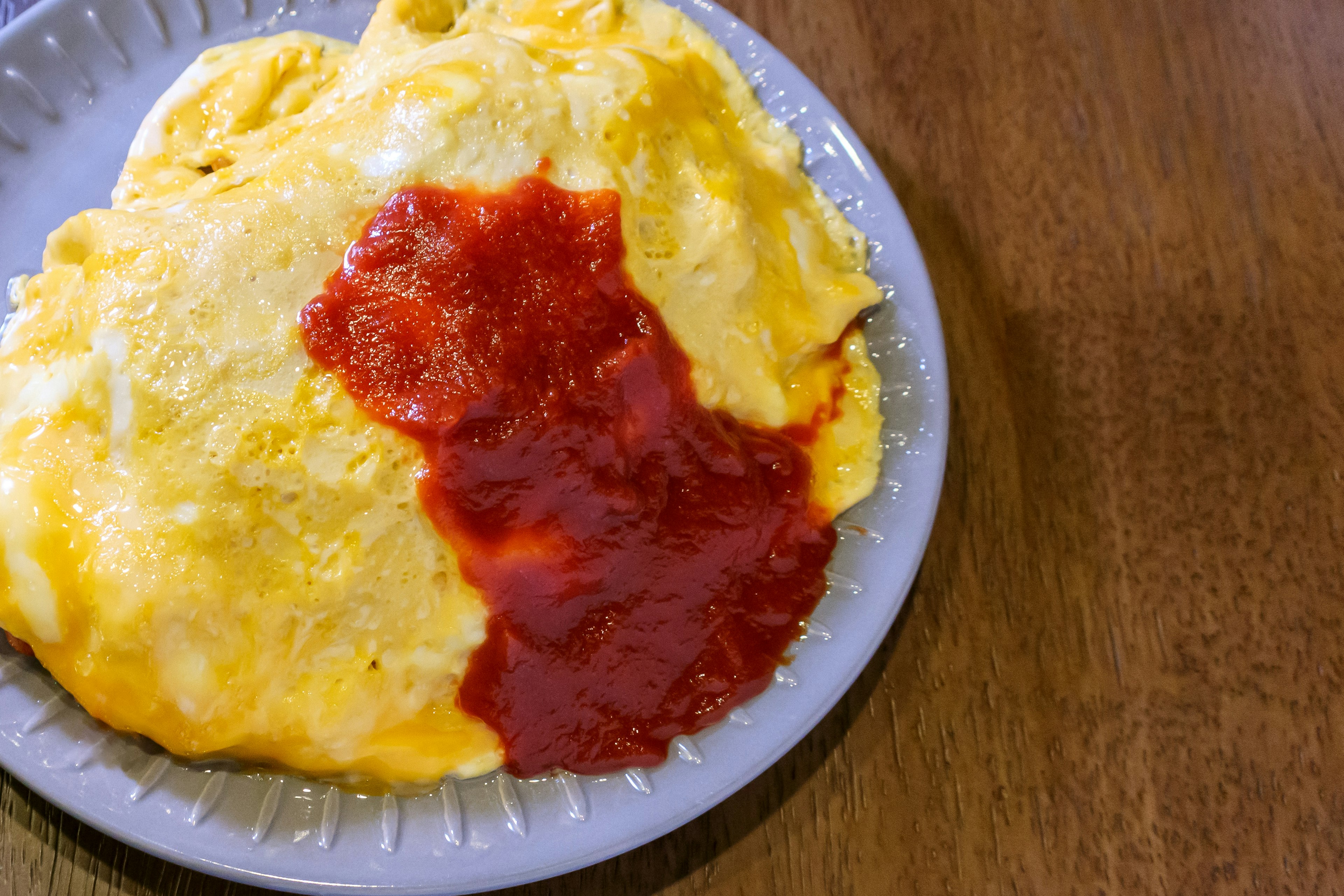 Piring omurice dengan saus tomat di atasnya