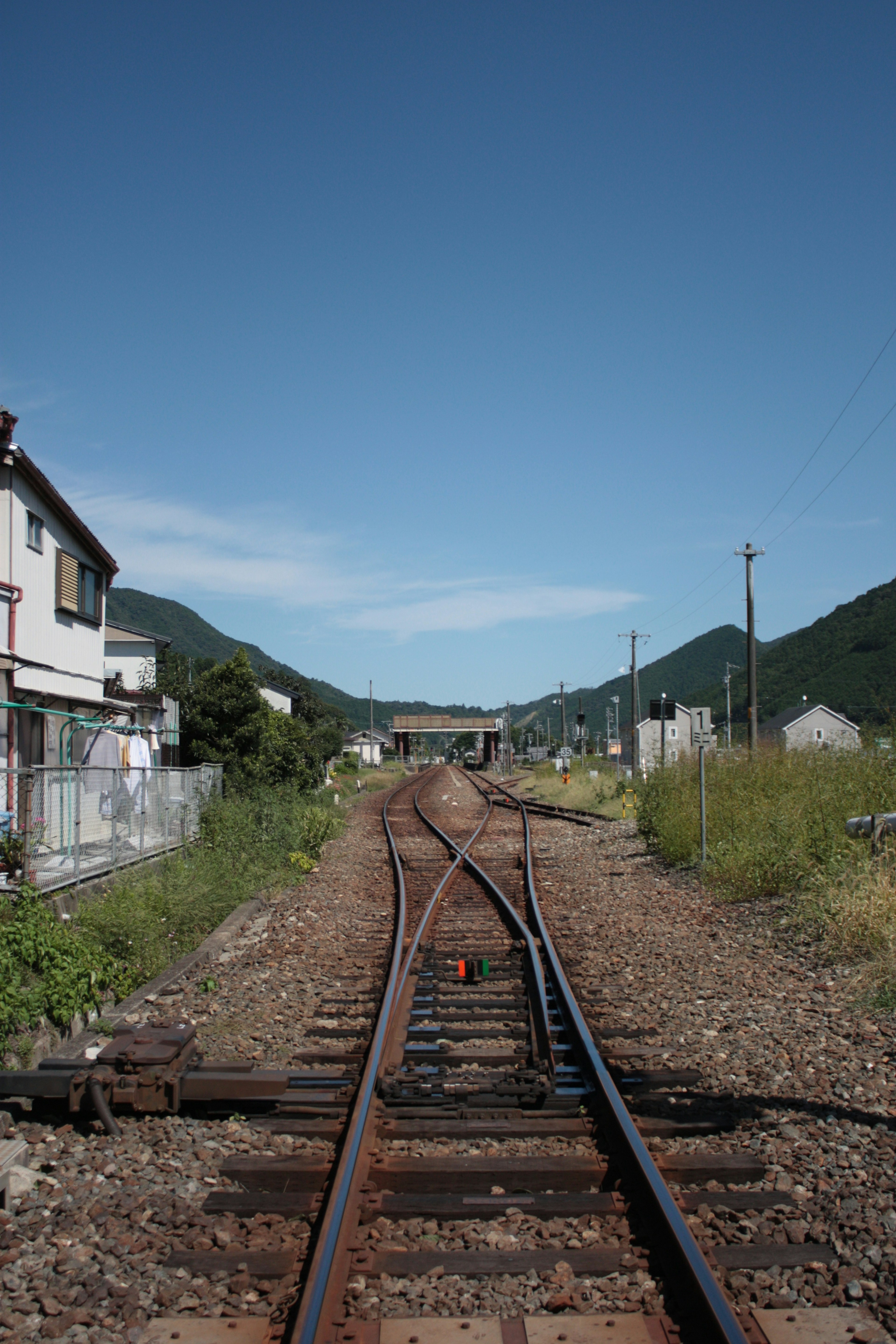 Railroad track junction surrounded by mountains and houses