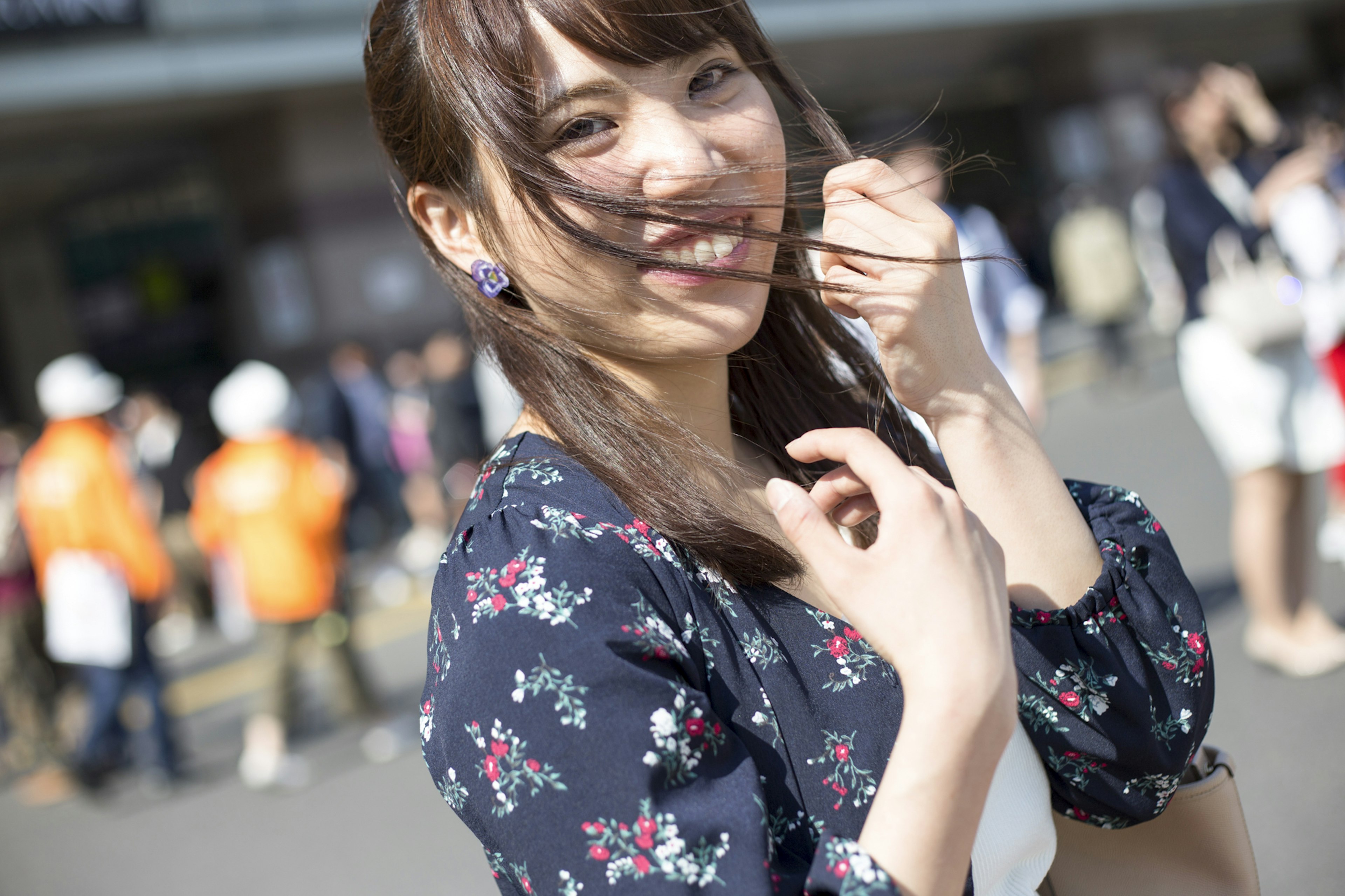 Young woman smiling and playing with her hair in a floral dress