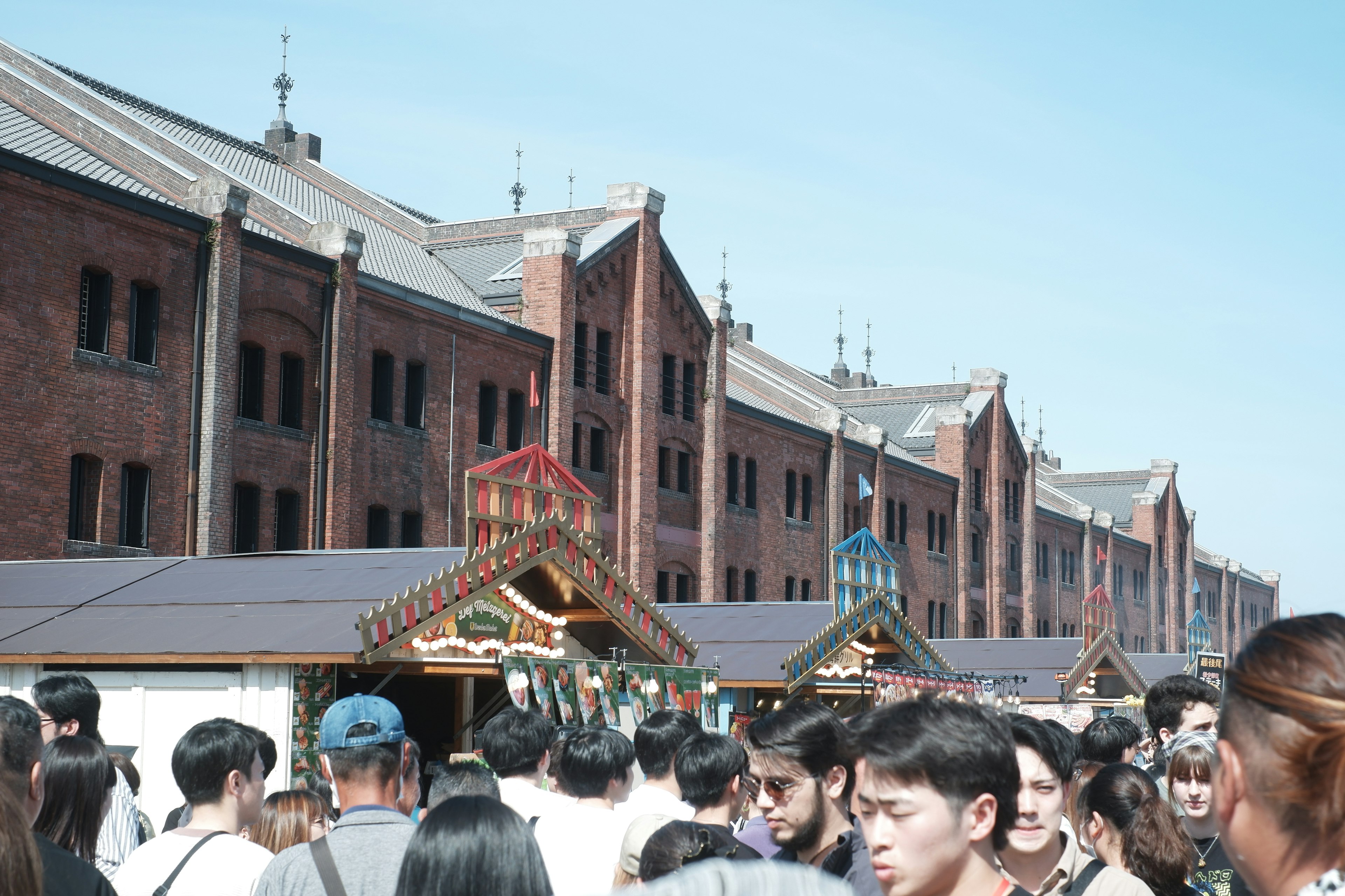 賑やかな屋台と赤レンガの建物が並ぶ風景