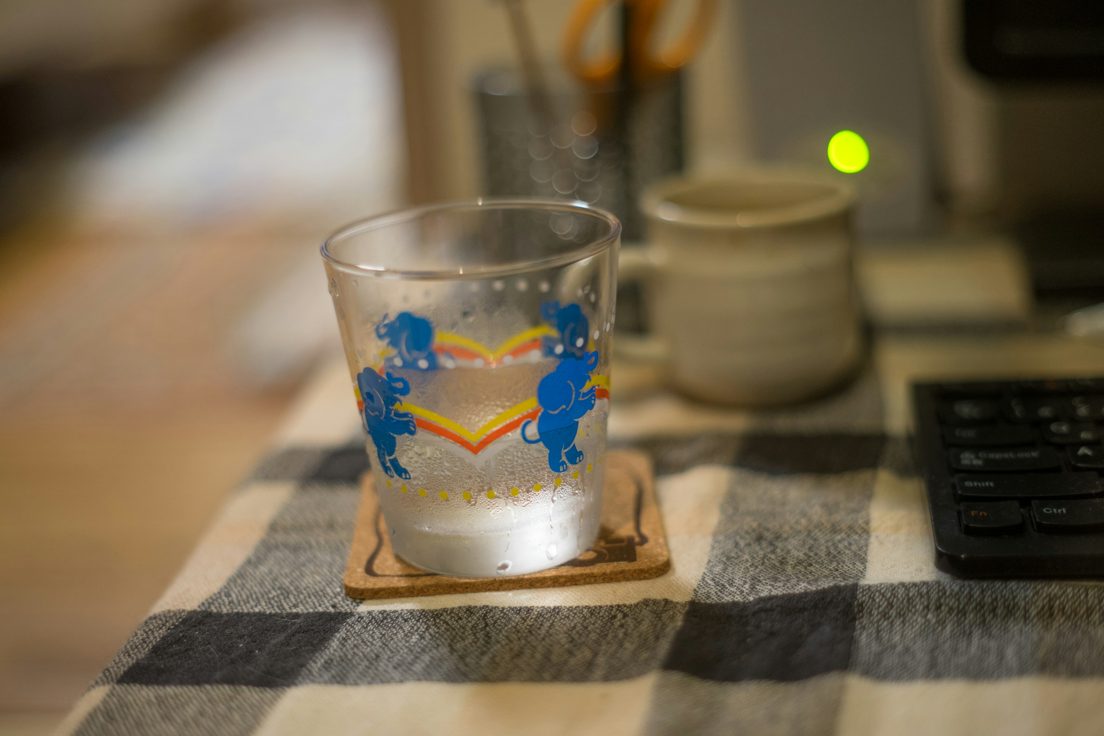 A clear glass with blue character illustrations filled with a drink on a table