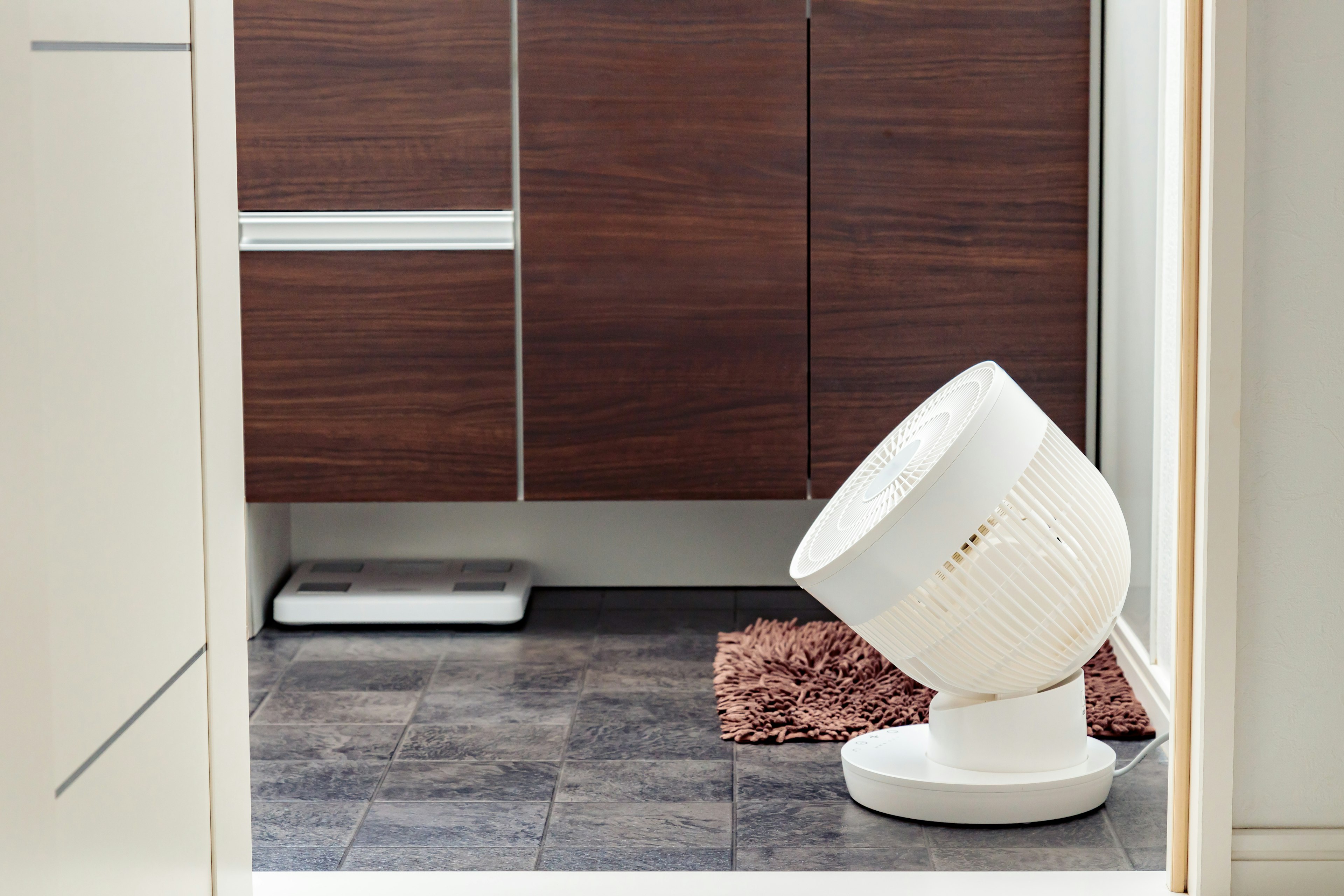 A modern kitchen featuring a white automatic cat feeder and a brown mat