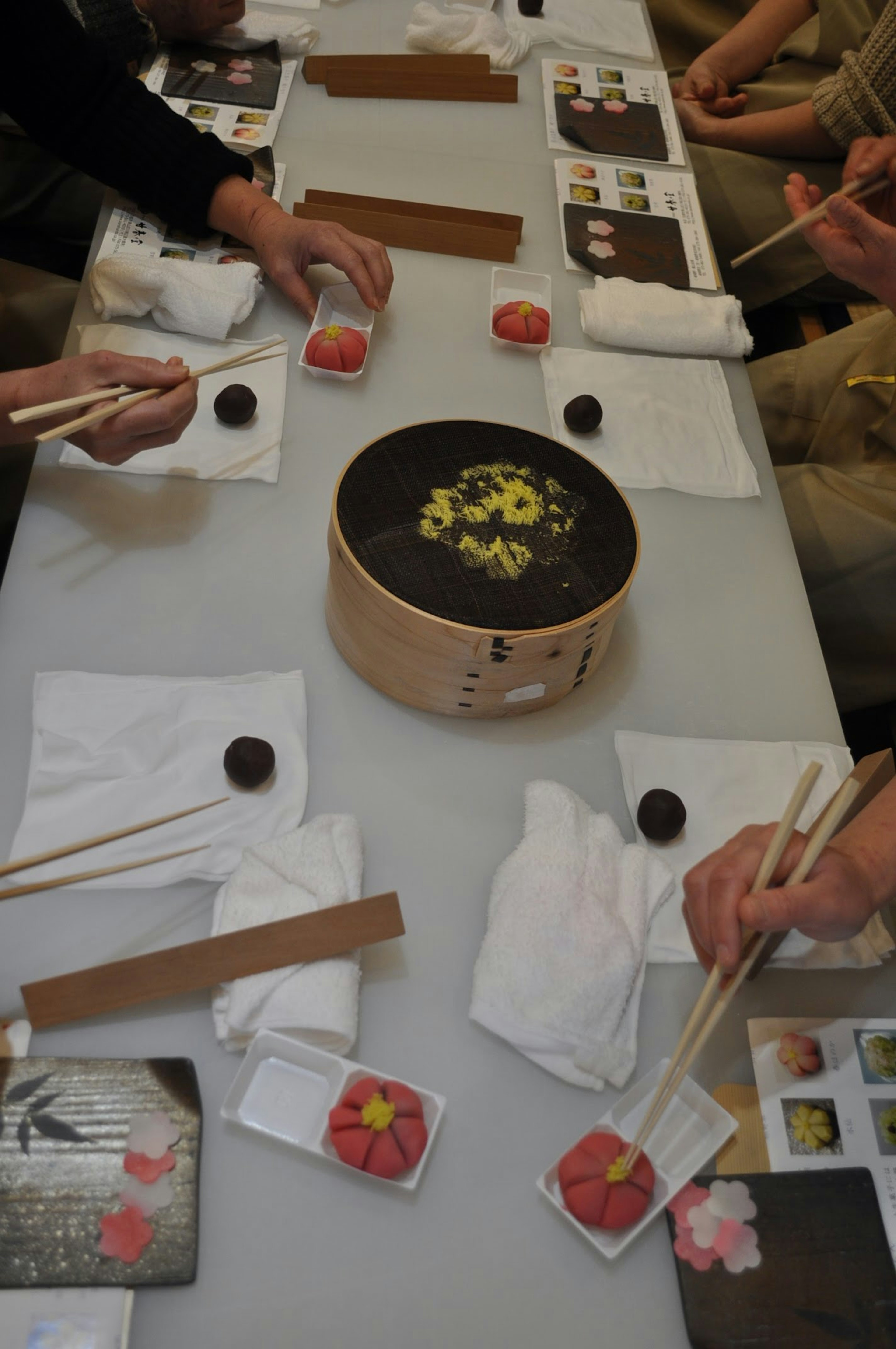 Hände von Personen, die traditionelle japanische Süßigkeiten an einem Tisch genießen