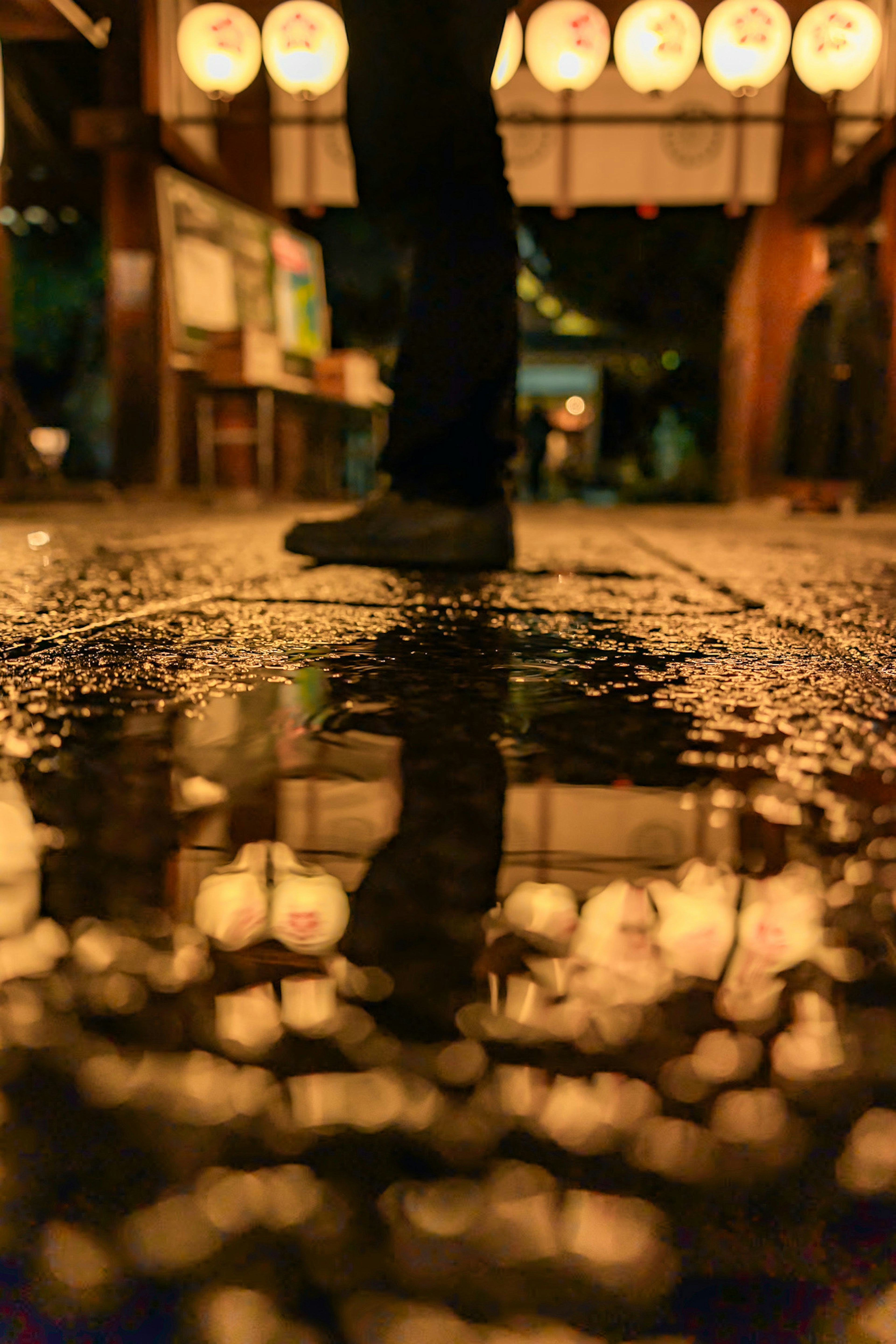 Reflejo de una figura en una superficie mojada con linternas brillantes de fondo