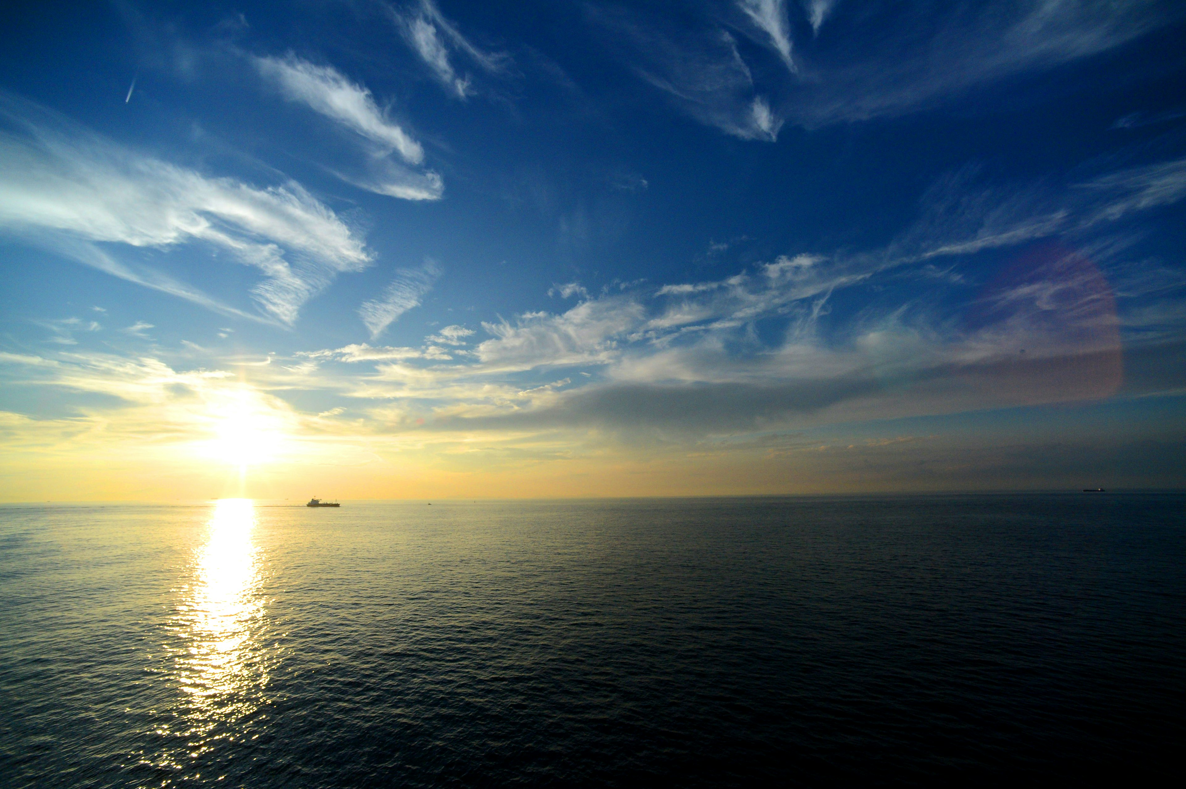 Vue panoramique de l'océan avec un ciel bleu et un coucher de soleil se reflétant sur l'eau