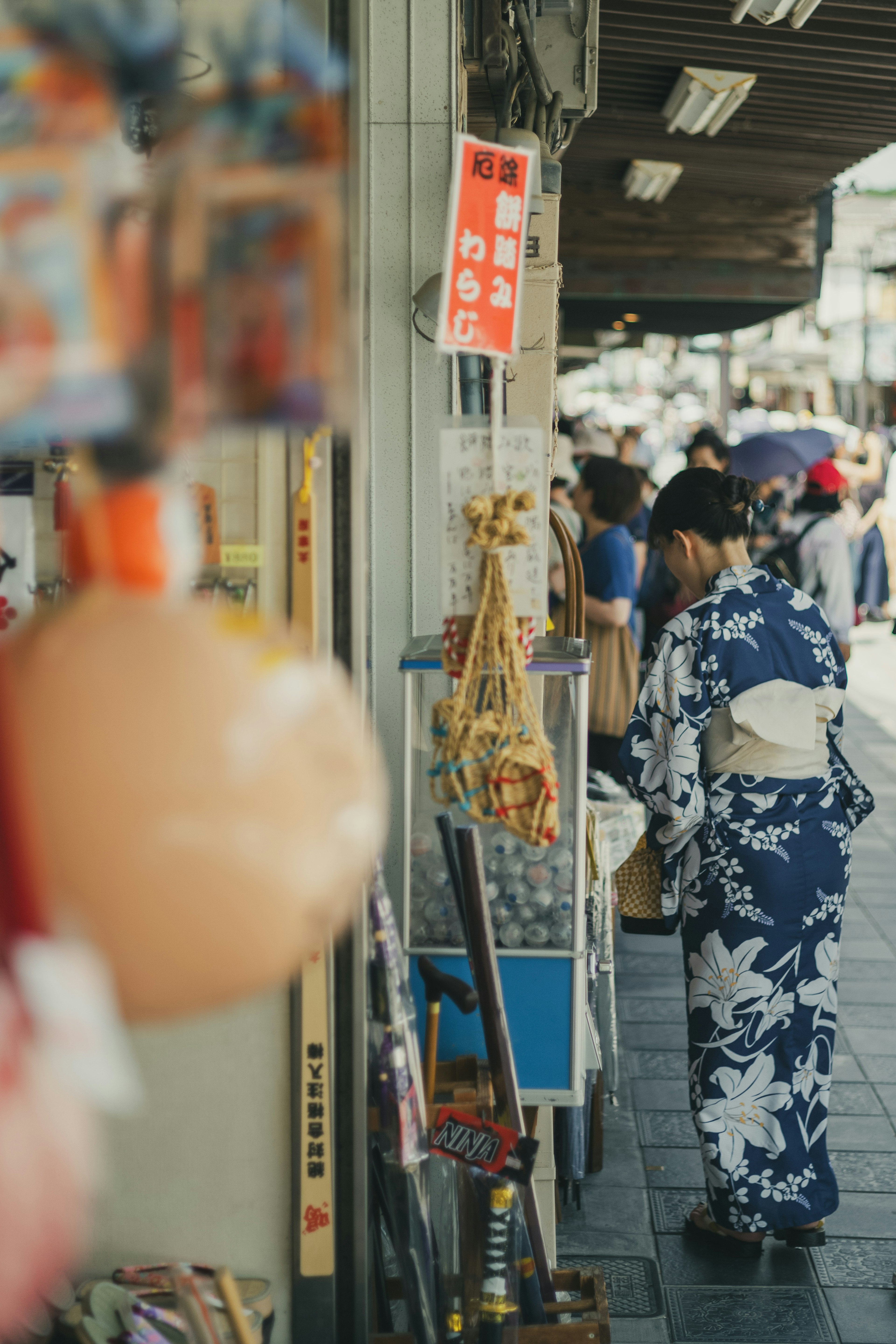 Người phụ nữ trong kimono đi dạo trên phố nhộn nhịp có các cửa hàng