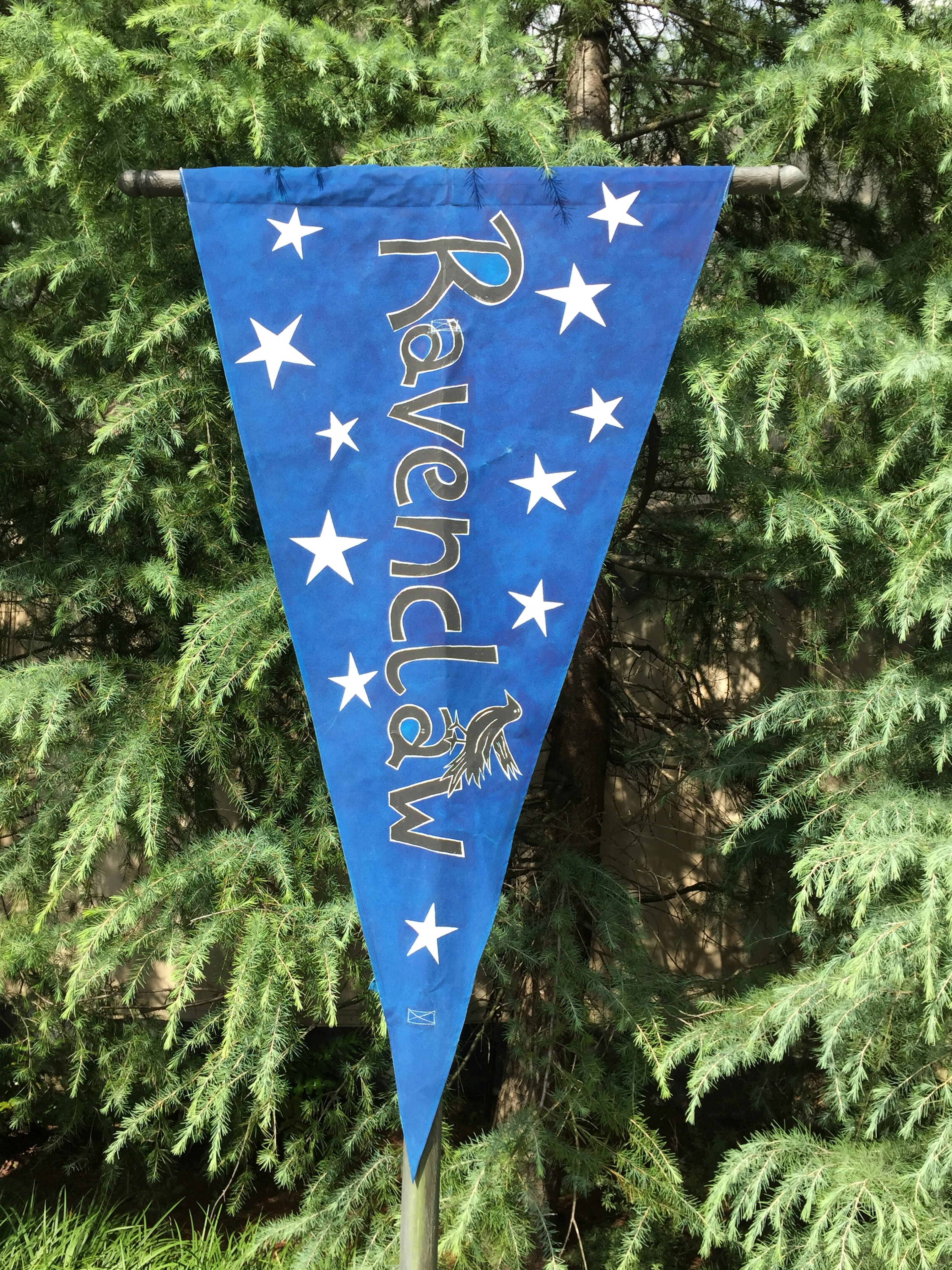 Bandera triangular azul con estrellas blancas y el nombre 'Ravenclaw'