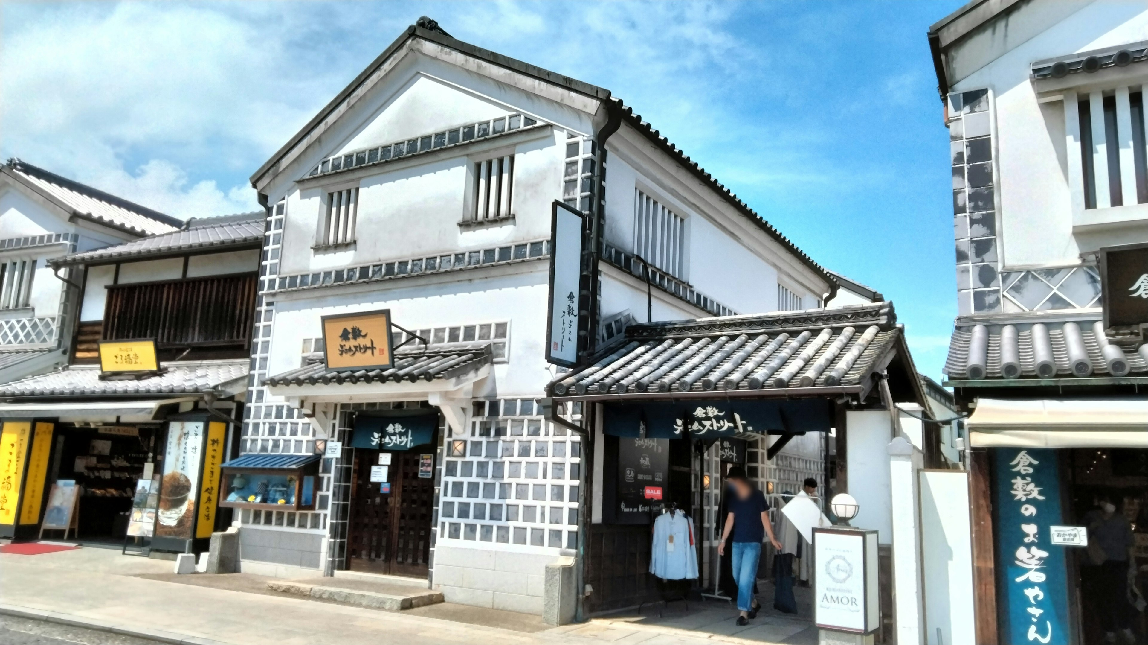 Edificio japonés tradicional con paredes blancas y techo negro en una calle comercial